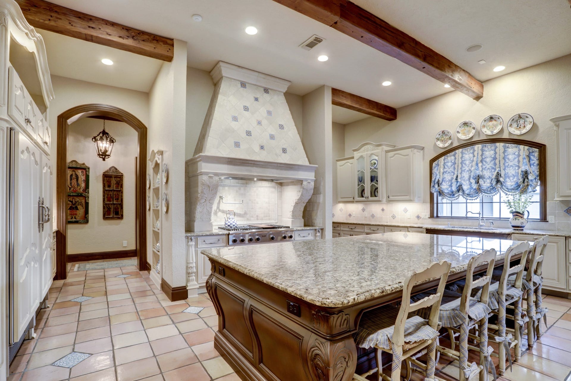 36 Saddlebrook Court, Tomball, TX 77375 Intricate details adorn the kitchen including custom plaster vent hood and French hand-painted tile backsplash and reclaimed Saltillo tile floors enhancing the old world authenticity of the home.