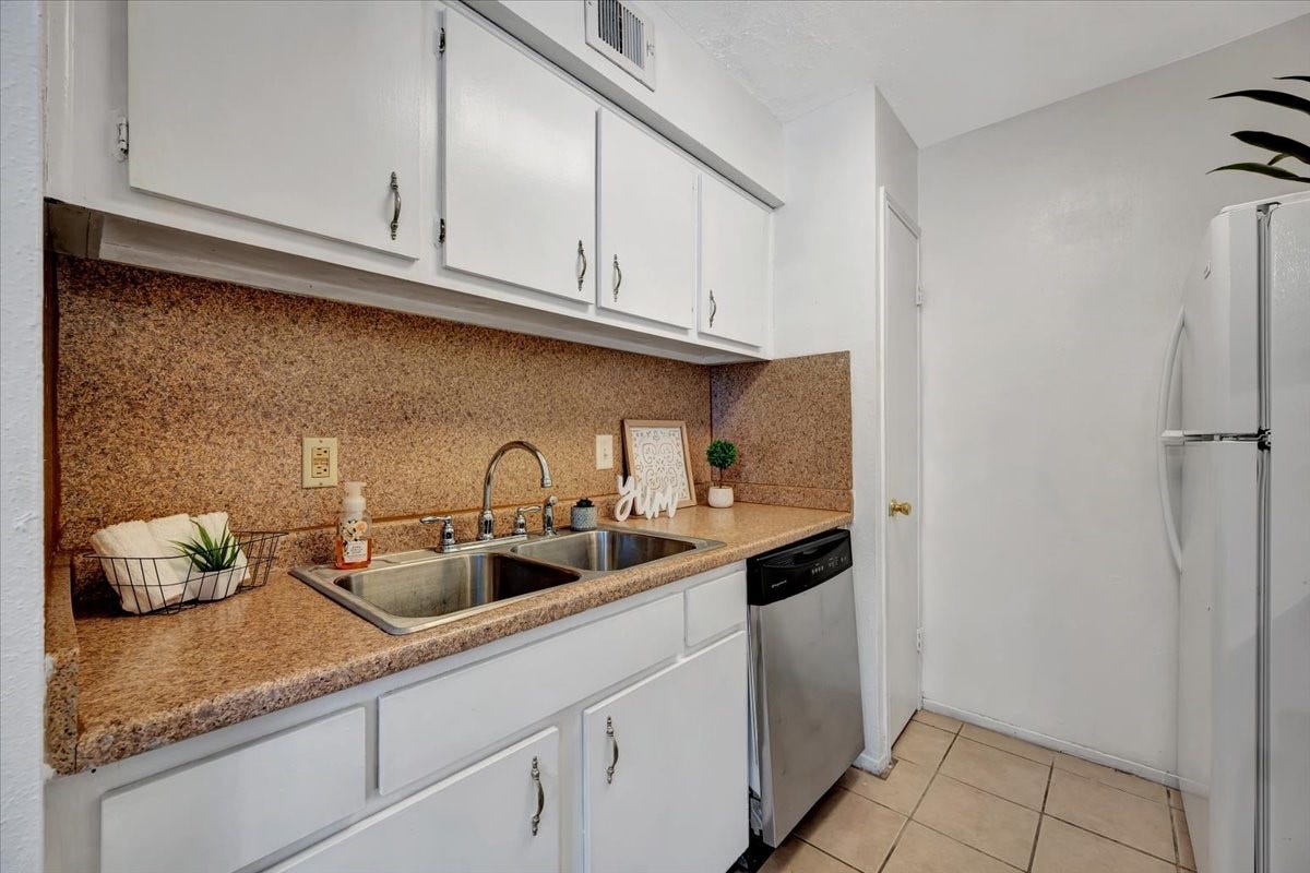 Featuring white cabinets with handles for easy use, a recently replaced electric stove, a dishwasher, and a refrigerator included with the unit.