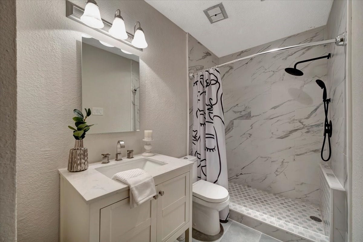 Step into this beautifully remodeled bathroom, featuring an enlarged tiled shower with modern finishes and a sleek, contemporary design.