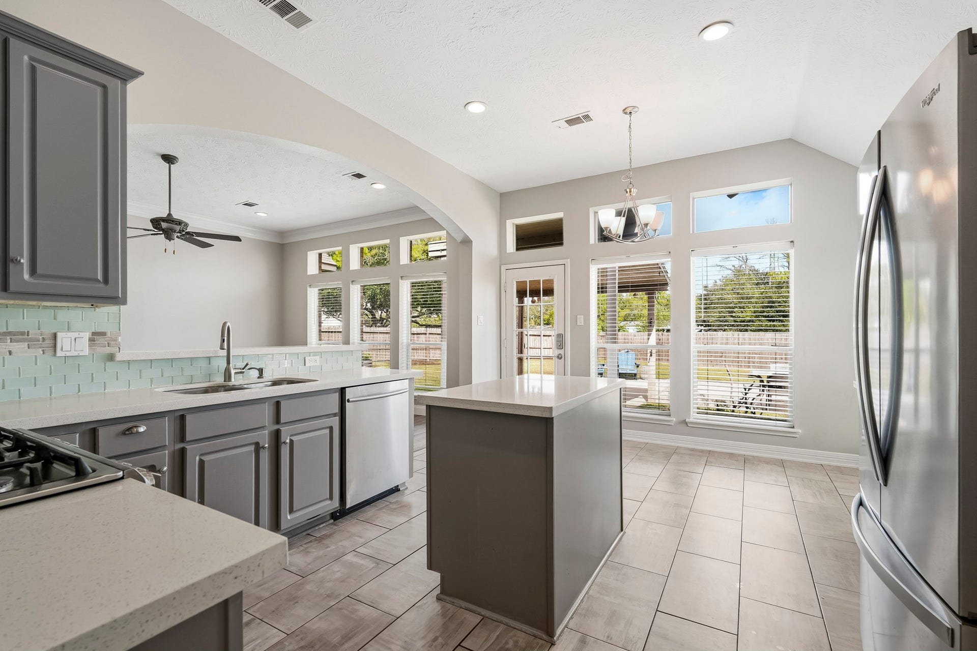 Updated kitchen featuring quartz countertops, a center island, ample cabinetry, and a freestanding gas range.