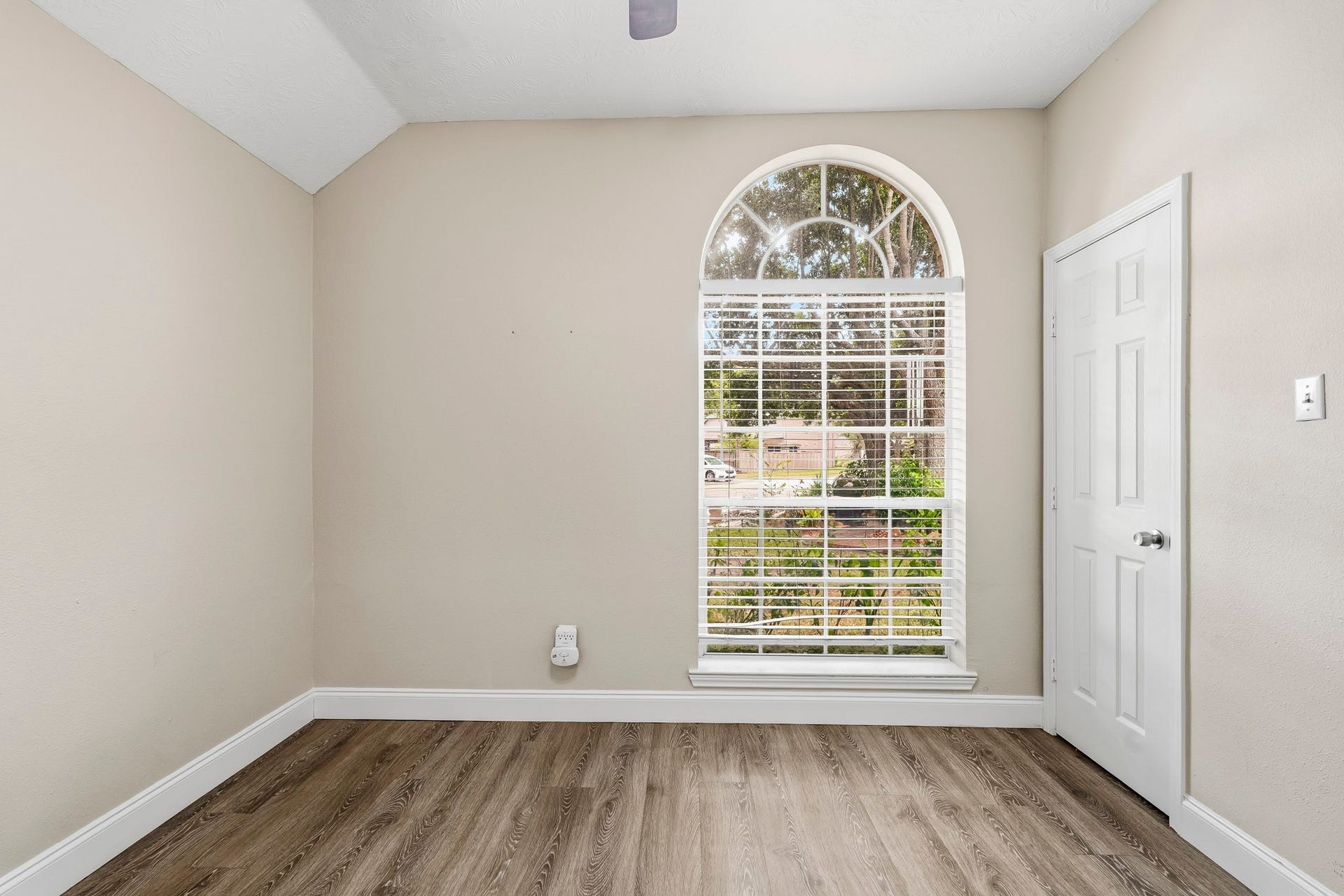 Comfortable secondary bedroom featuring neutral tones, wood-look flooring, and a ceiling fan.