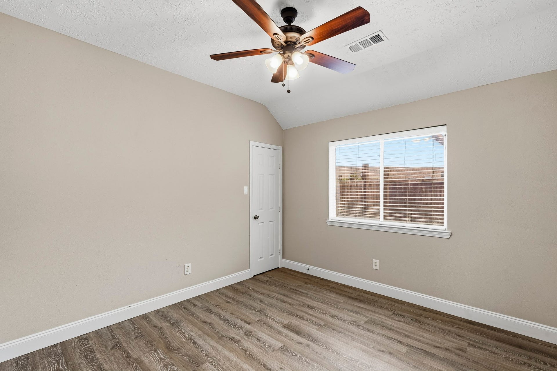 Comfortable secondary bedroom featuring neutral tones, wood-look flooring, and a ceiling fan.