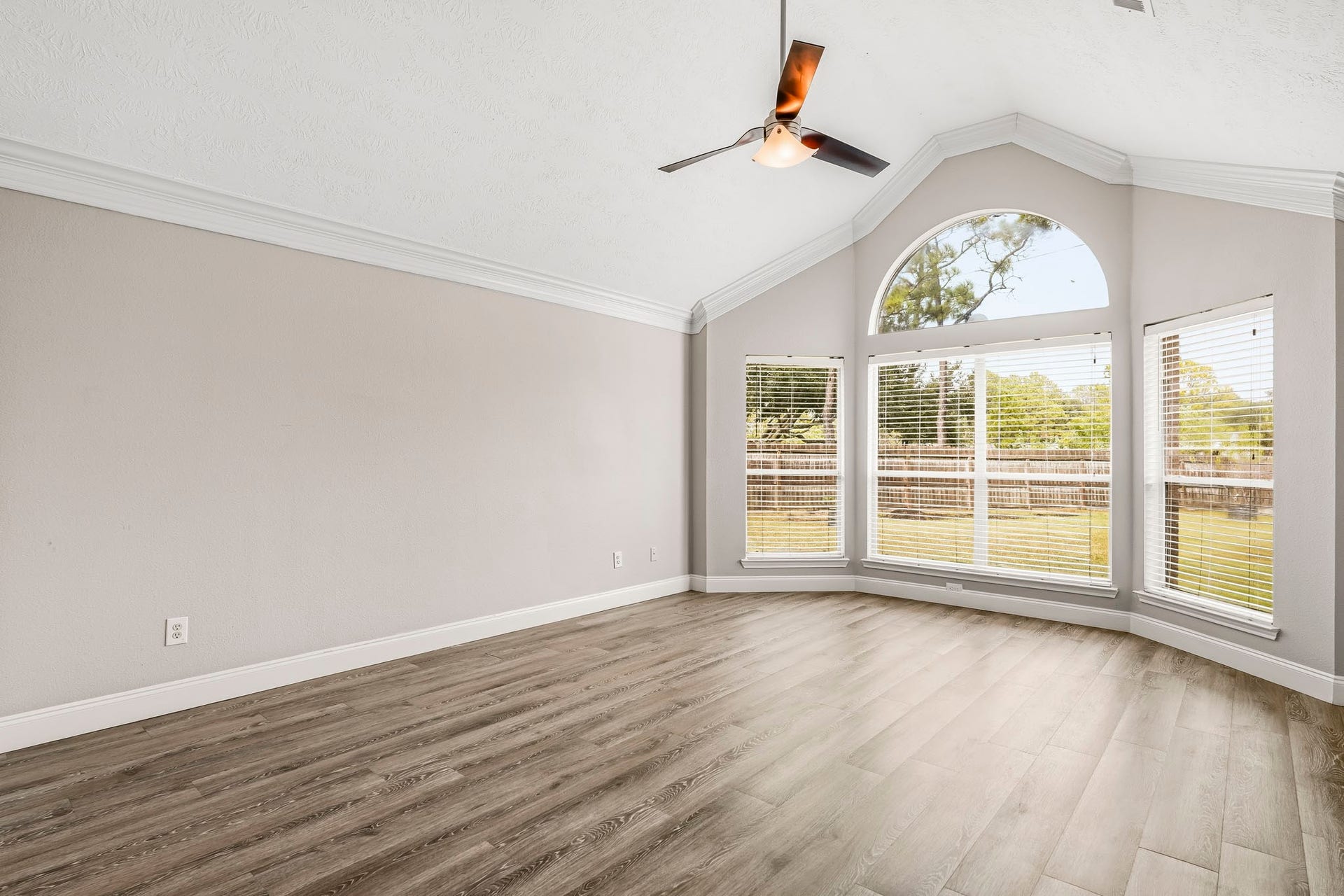 Generously sized primary suite with vaulted ceilings, a ceiling fan, and a beautiful bay window overlooking the backyard.