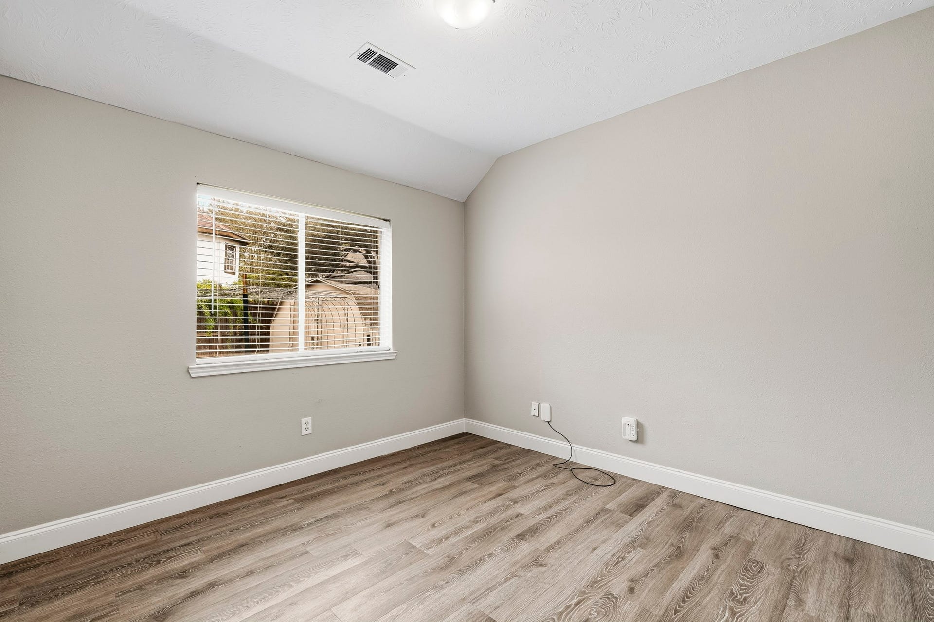 Comfortable secondary bedroom featuring neutral tones, wood-look flooring, and a ceiling fan.