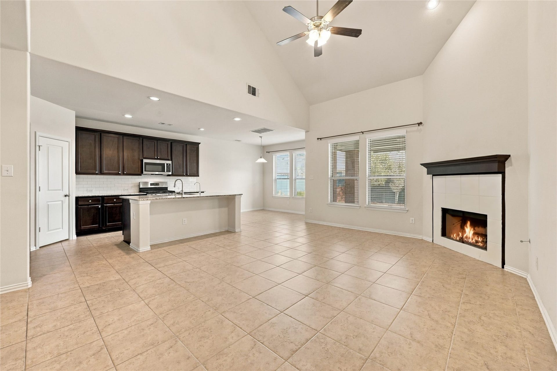This stunning open concept living area features soaring ceilings, abundant natural light, and a cozy fireplace, flowing seamlessly into the kitchen and dining space. Perfect for everyday living and entertaining!