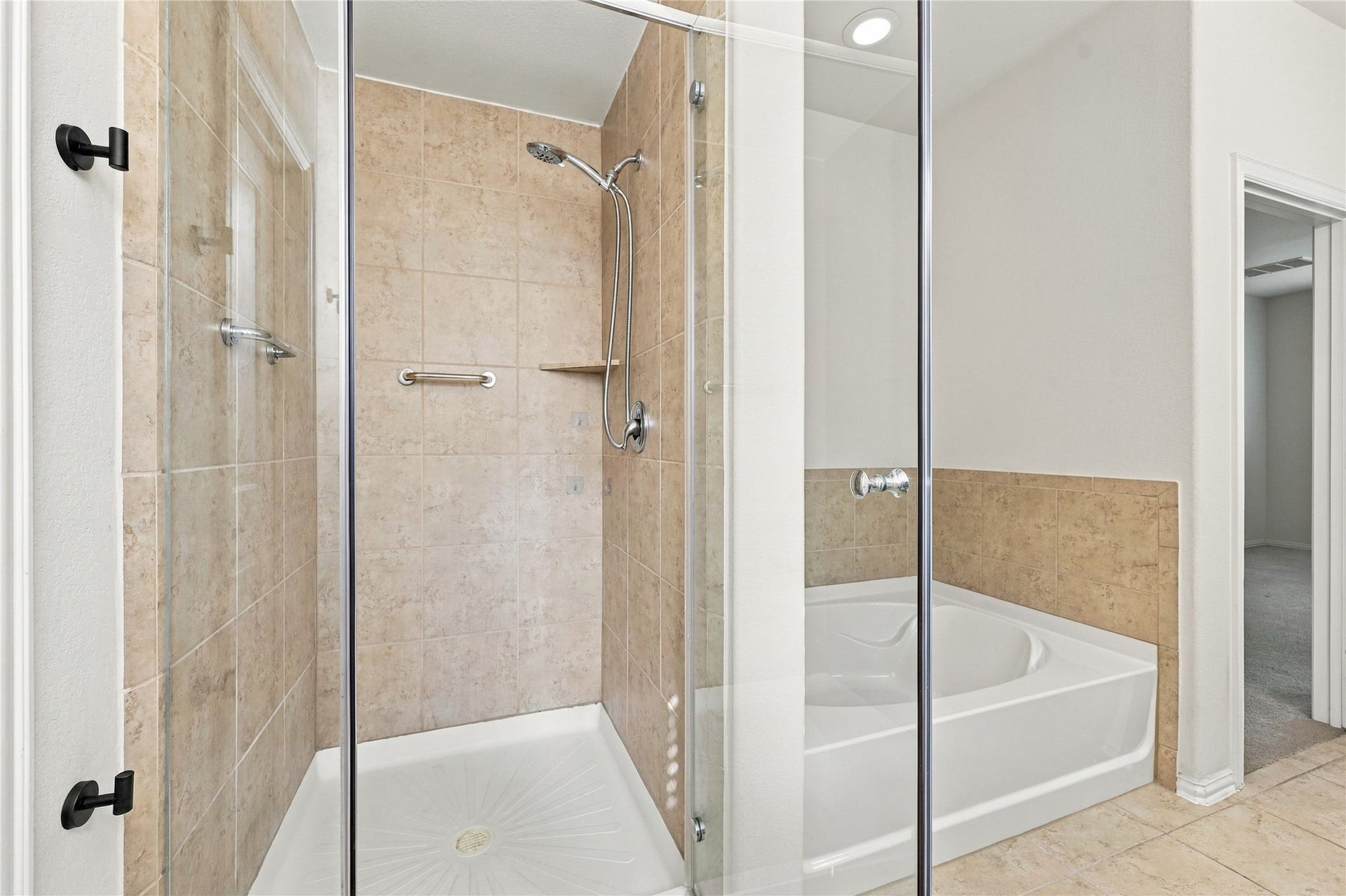 Primary bathroom features a spacious walk in shower with glass enclosure and a separate soaking tub, offering the perfect space to relax and unwind!
