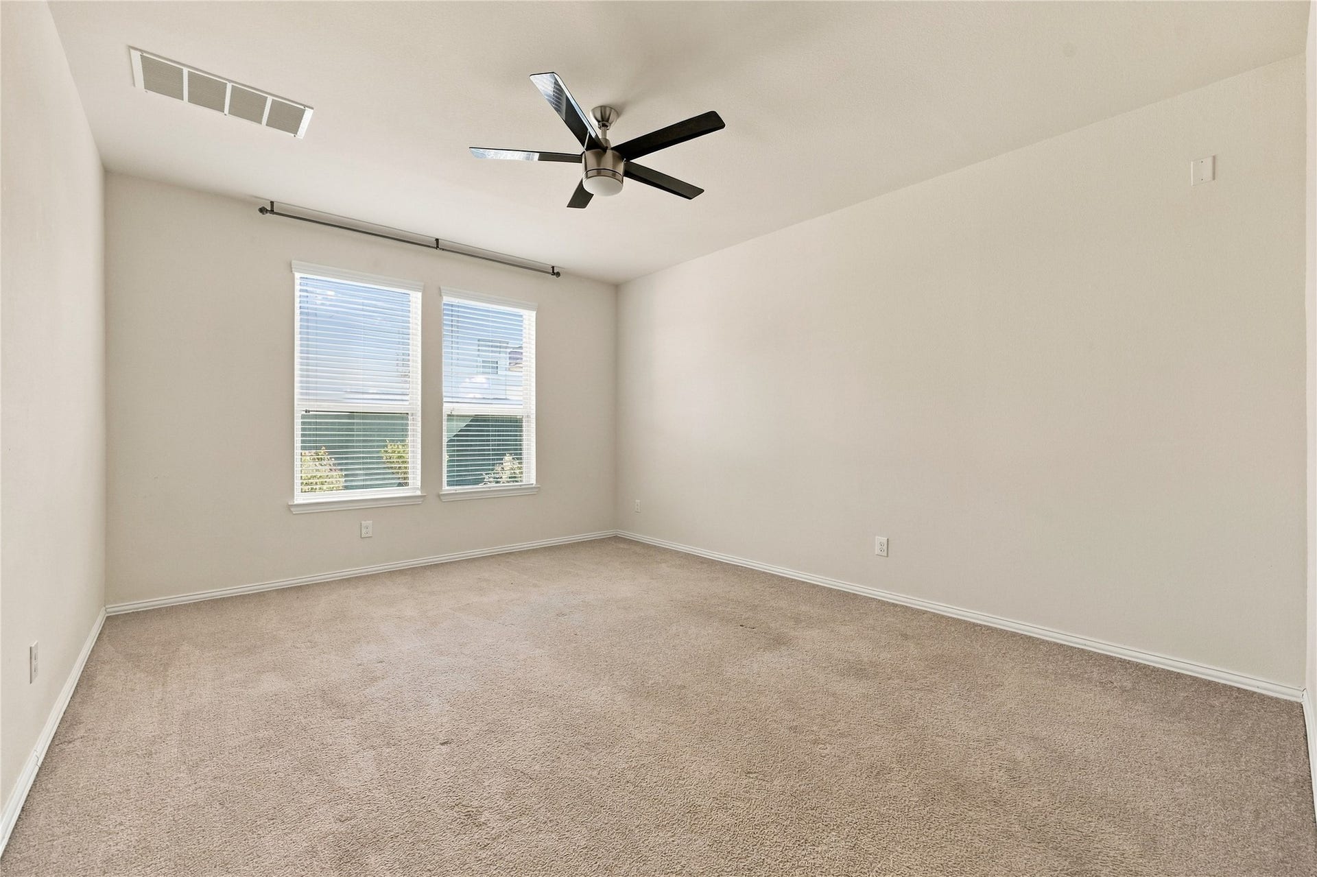 The spacious primary bedroom offers a peaceful retreat with neutral finishes,  a modern ceiling fan, and large windows that fill the room with natural light!
