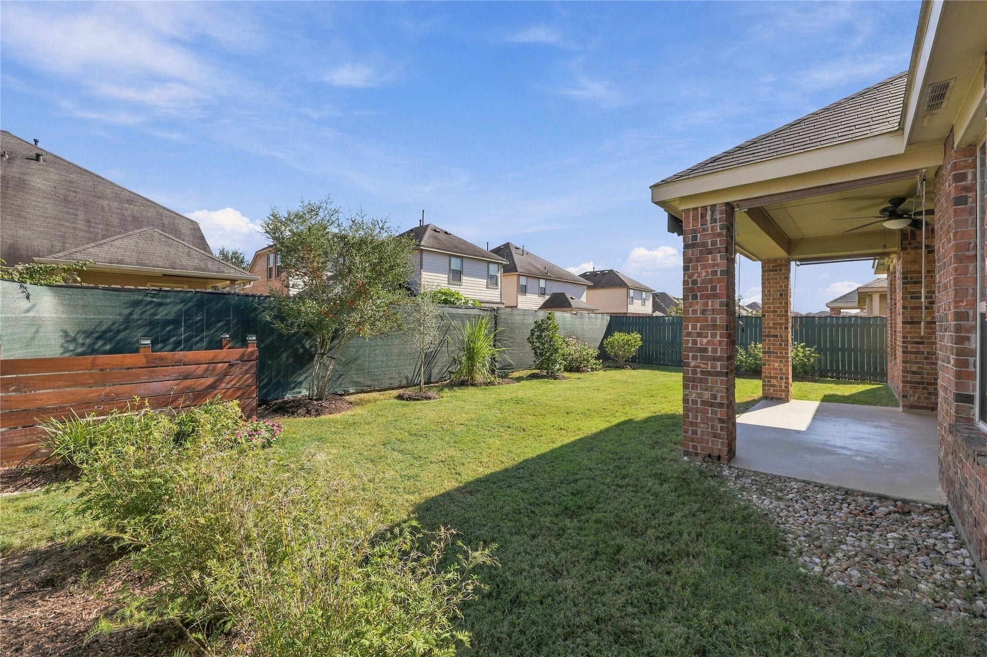 Enjoy this beautifully maintained backyard featuring lush green grass, established landscaping, and a spacious covered patio with plenty of room for outdoor entertaining and relaxation!