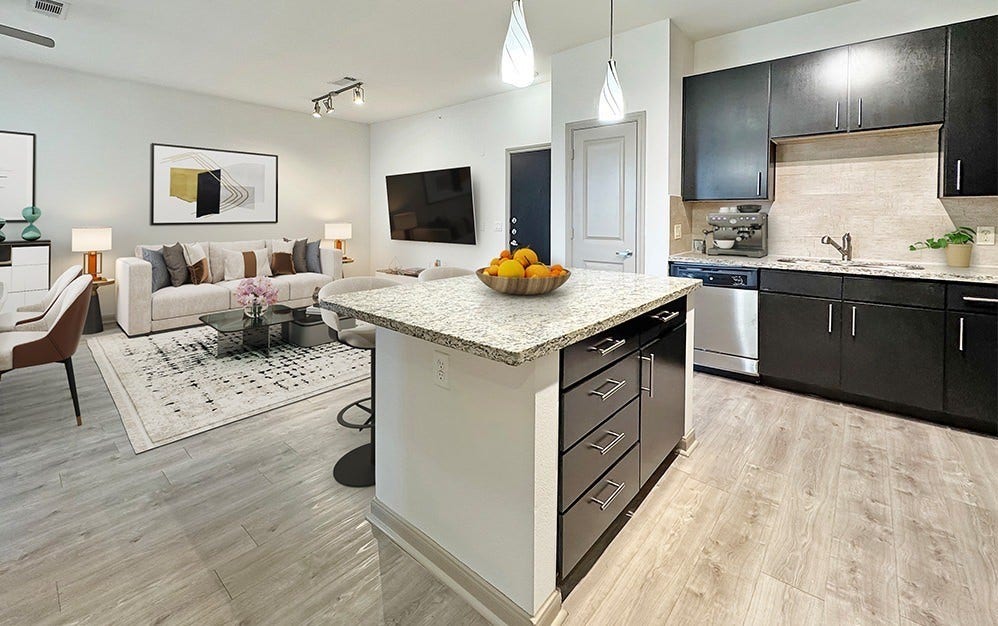 Sleek designer kitchen with granite countertops, stainless steel appliances, rich cabinetry and an oversized island that opens seamlessly to the living area.