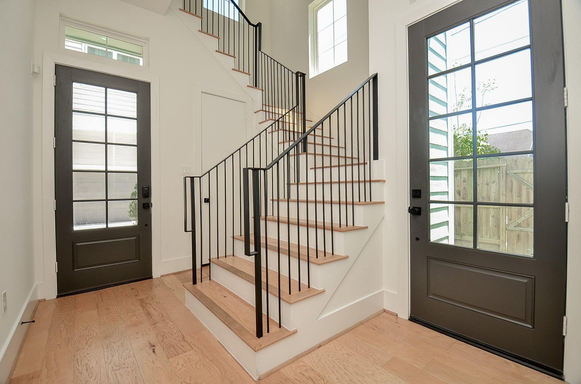 204 Burr Street, #G, Houston, TX 77011 Ground-floor entry with wood flooring, coat closet, access to backyard, and a beautiful staircase with iron spindles leading to the main living area.
