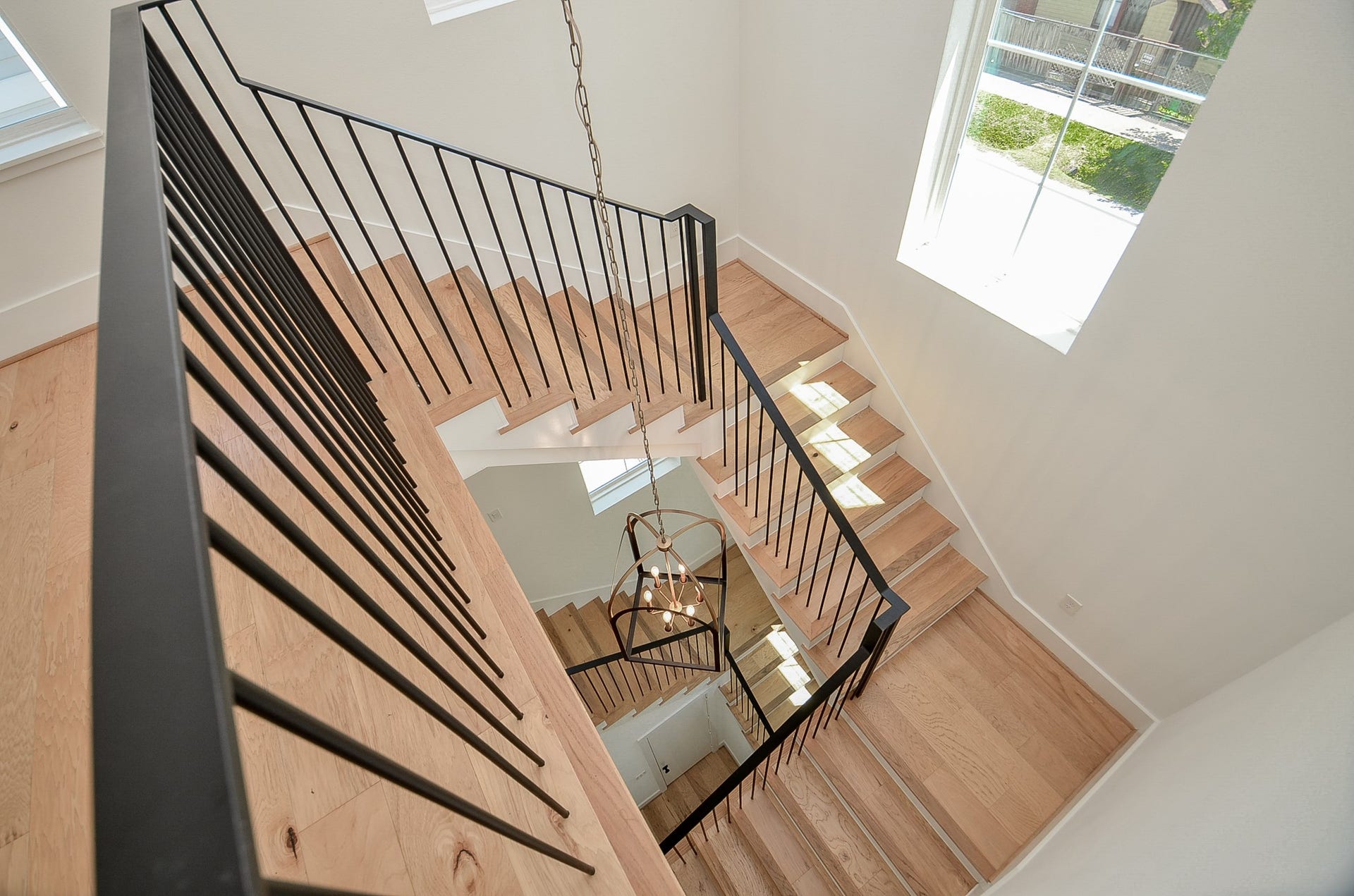 204 Burr Street, #G, Houston, TX 77011 From the top of the staircase, enjoy a striking view spanning all three levels, highlighted by the rich wood steps and sleek black railings that add a bold, modern touch to the homes design.