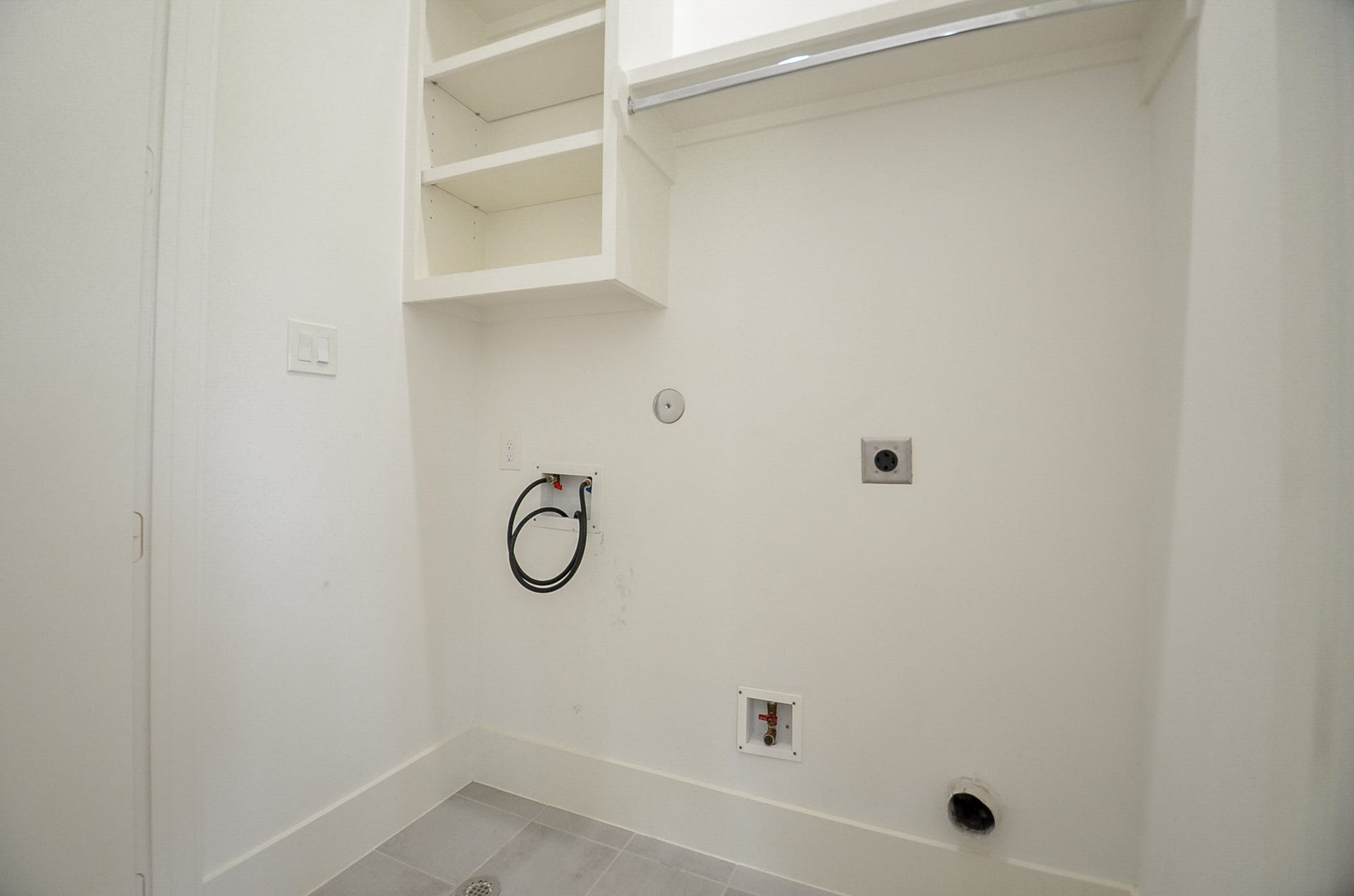 204 Burr Street, #G, Houston, TX 77011 Dedicated upstairs laundry space with built-in shelving and a hanging rod.