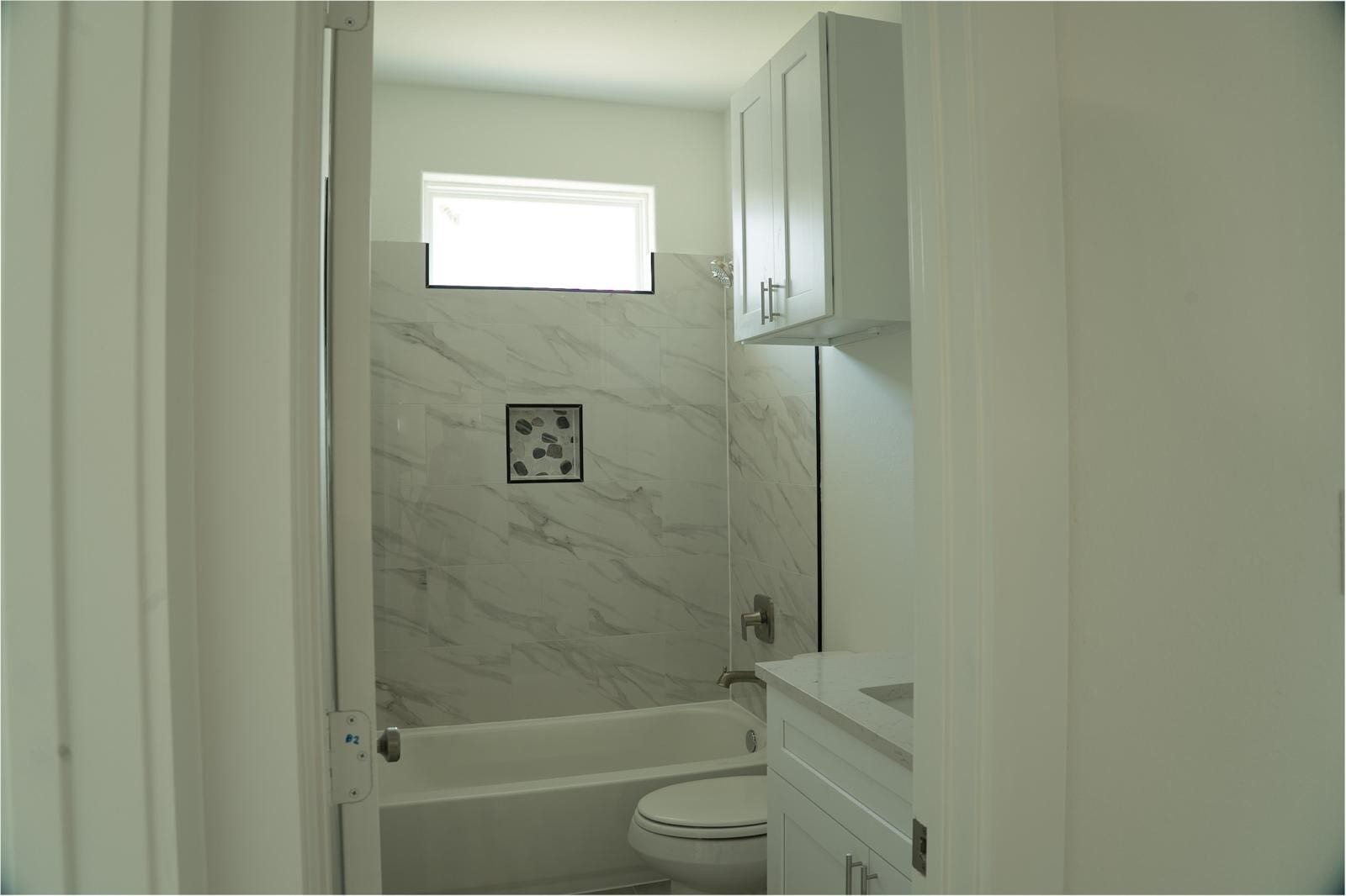 2306 Ridgewood Drive Drive, West Columbia, TX 77486 Bright and modern bathroom featuring elegant marble-style tile, a sleek vanity, and ample natural light through a high window.