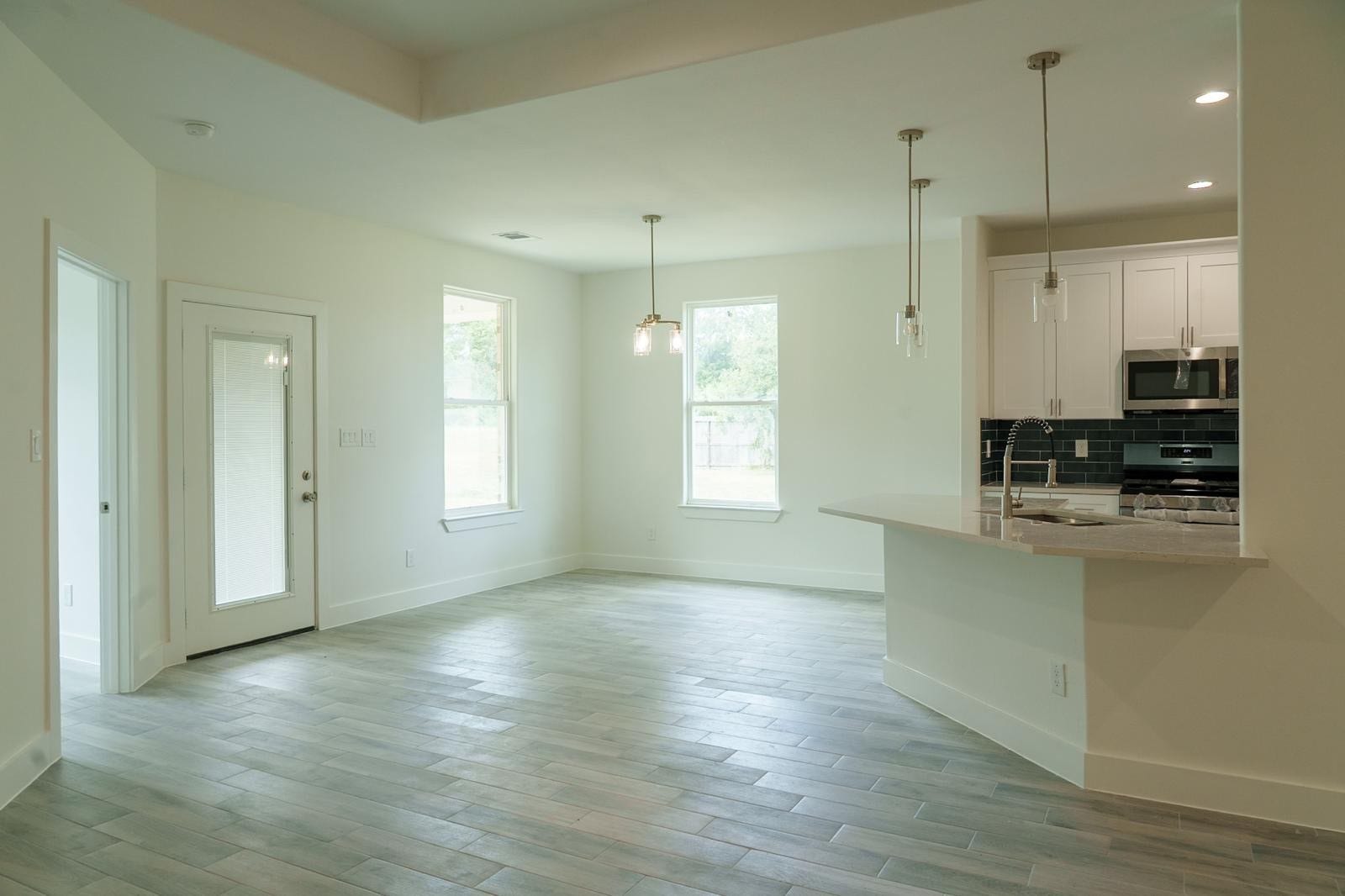 2306 Ridgewood Drive Drive, West Columbia, TX 77486 Bright and airy open-concept living space featuring modern pendant lighting, sleek tile flooring, and a stylish kitchen with a breakfast bar and stainless steel appliances.