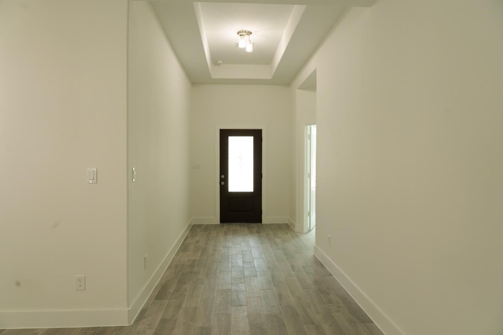 2306 Ridgewood Drive Drive, West Columbia, TX 77486 Inviting foyer with a modern dark door, high ceilings, and sleek wood-look tile flooring, offering a bright and spacious entryway.