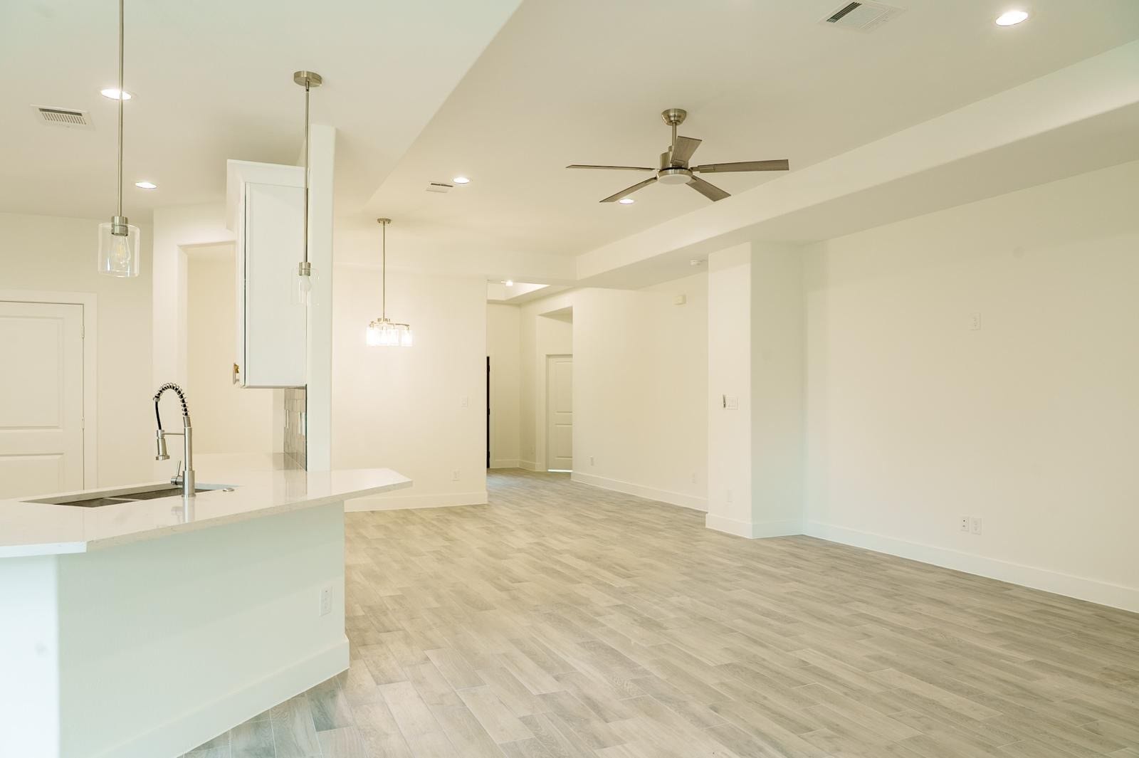 2306 Ridgewood Drive Drive, West Columbia, TX 77486 Spacious open-concept living area with sleek wood flooring, modern ceiling fan, and a stylish kitchen featuring a central island and elegant pendant lighting.