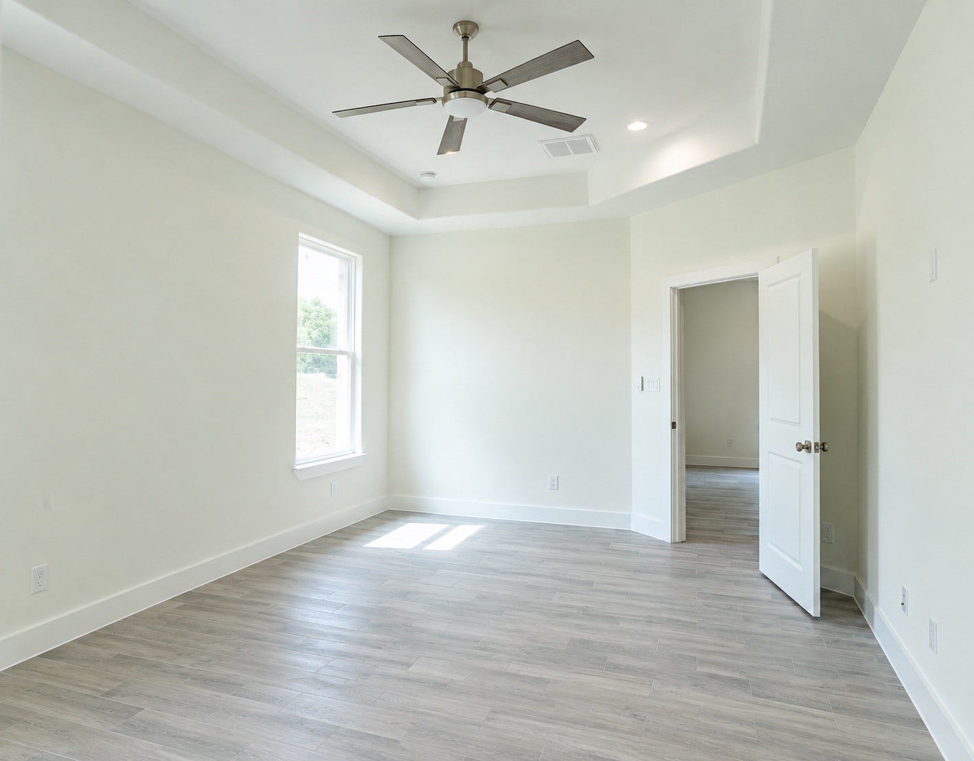 2306 Ridgewood Drive Drive, West Columbia, TX 77486 Bright and airy room featuring elegant wood flooring, a modern ceiling fan, and ample natural light from the large window.