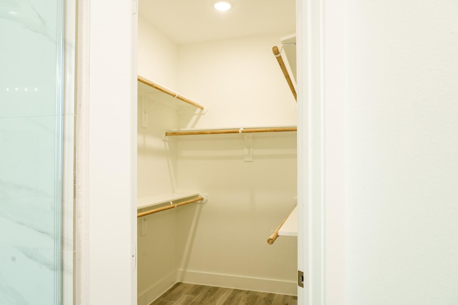 2306 Ridgewood Drive Drive, West Columbia, TX 77486 Spacious walk-in closet with ample shelving and hanging space, highlighted by warm wood accents and bright lighting.