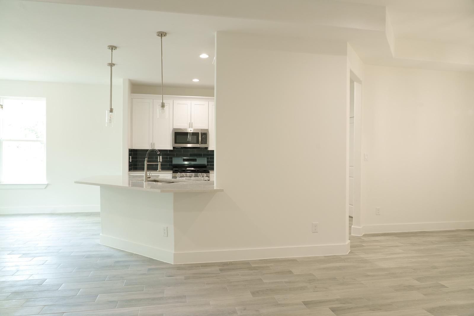 2306 Ridgewood Drive Drive, West Columbia, TX 77486 Bright and modern kitchen with sleek white cabinetry, stylish black backsplash, and elegant pendant lighting over a spacious peninsula.