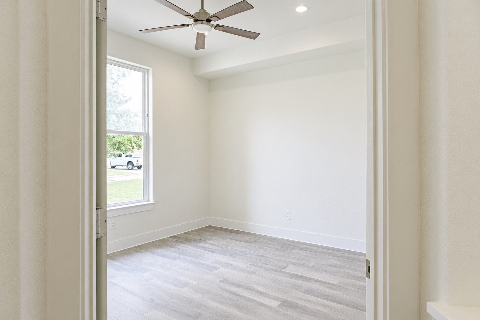2306 Ridgewood Drive Drive, West Columbia, TX 77486 Bright and inviting room with large window, modern ceiling fan, and sleek hardwood flooring.