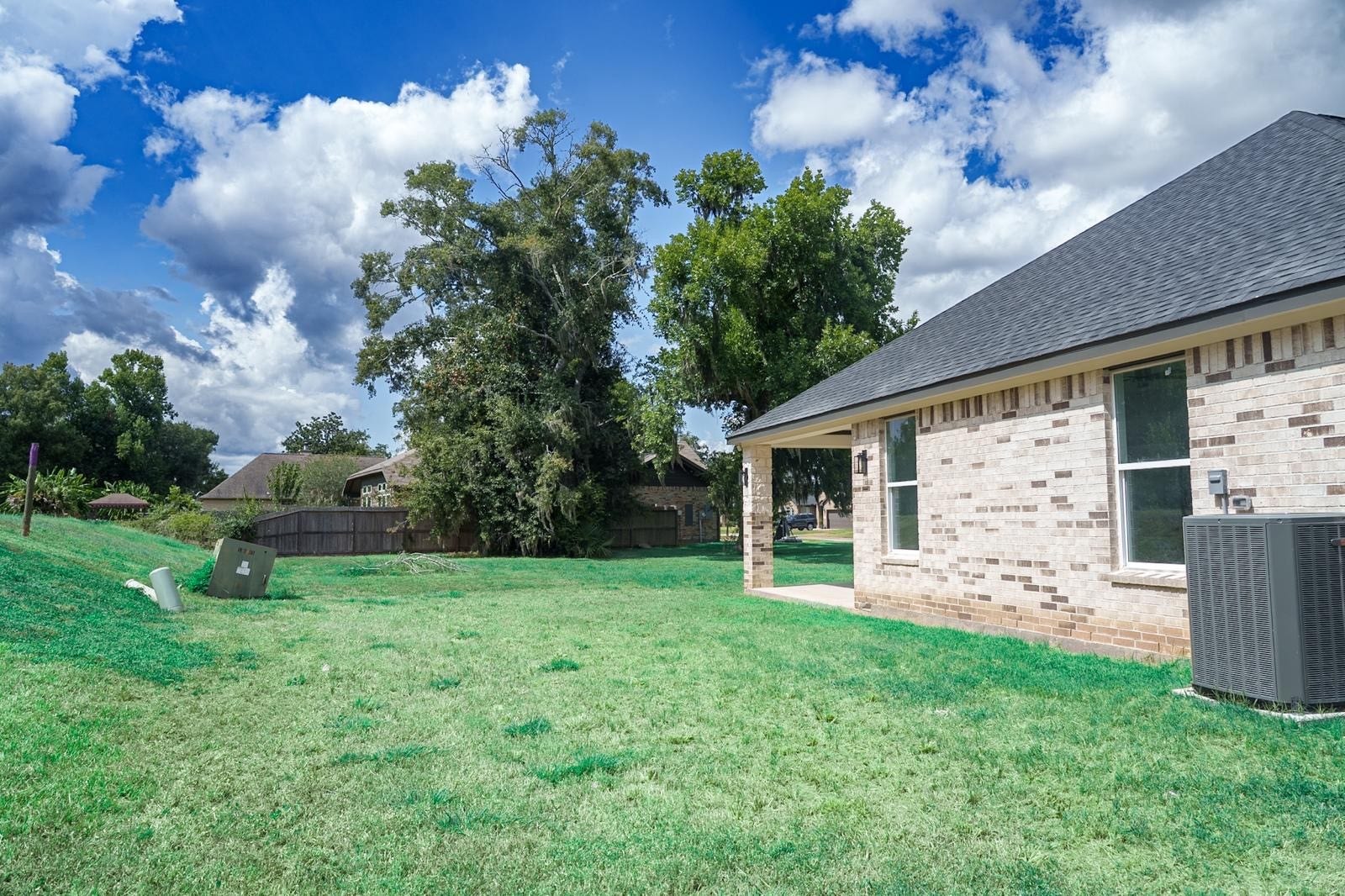 2306 Ridgewood Drive Drive, West Columbia, TX 77486 Spacious backyard with lush greenery and a charming brick exterior, perfect for outdoor activities and relaxation.