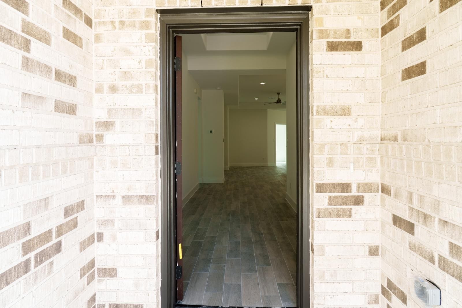 2306 Ridgewood Drive Drive, West Columbia, TX 77486 Inviting entryway with stylish brickwork and a view into the open, well-lit interior featuring sleek wood-look flooring.