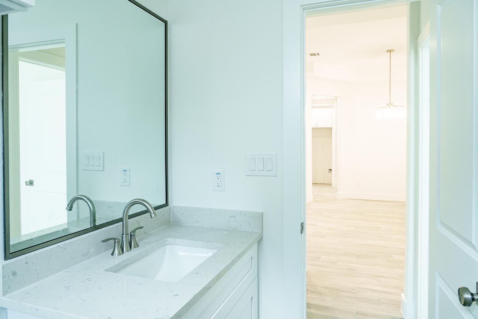2306 Ridgewood Drive Drive, West Columbia, TX 77486 Elegant bathroom with a sleek vanity and modern fixtures, opening into a bright, spacious room with stylish lighting and wood flooring.