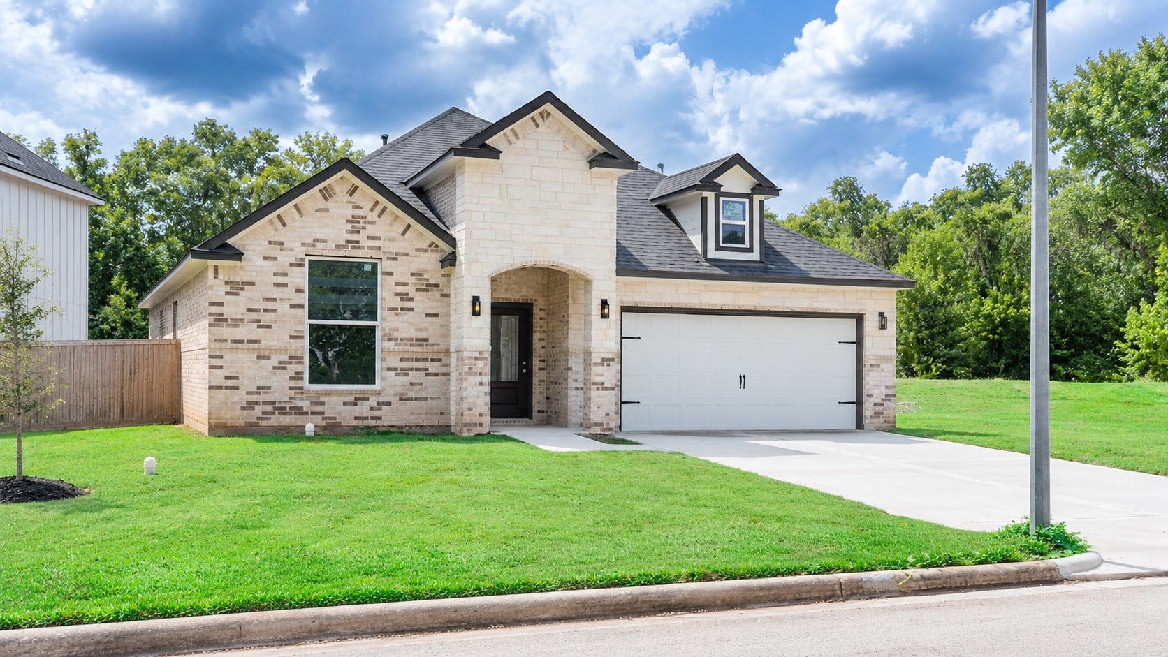 2306 Ridgewood Drive Drive, West Columbia, TX 77486 A single-story home featuring a blend of brick and stone exterior, a Spacious 2 car garage, and a well-maintained lawn, all set against a backdrop of lush greenery.