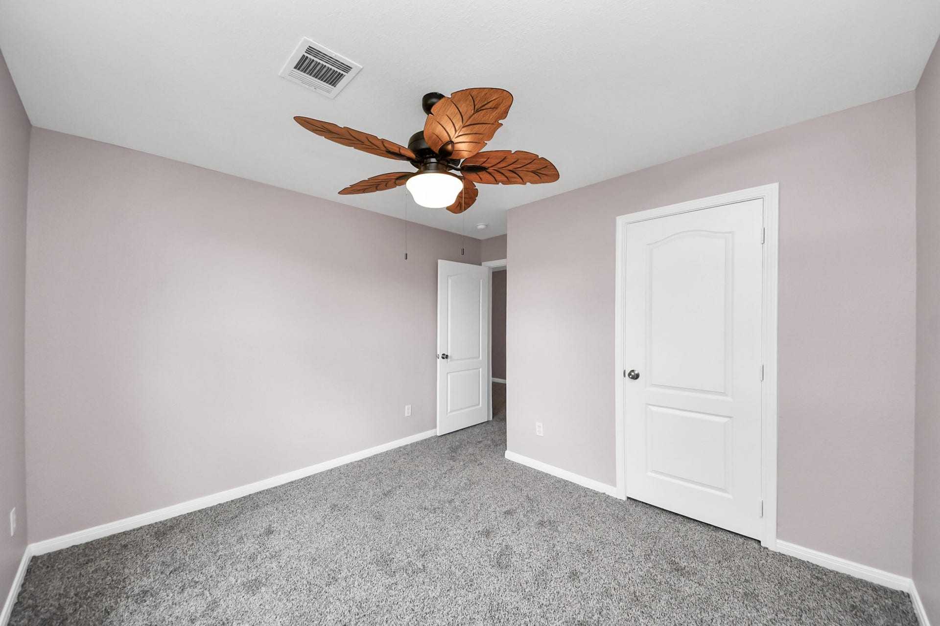 10026 Gil Jr Lane, Houston, TX 77075 Discover the charm of Bedroom #2, featuring soft lavender walls, plush carpeting, and a unique leaf-shaped ceiling fan that adds a touch of elegance and comfort.
