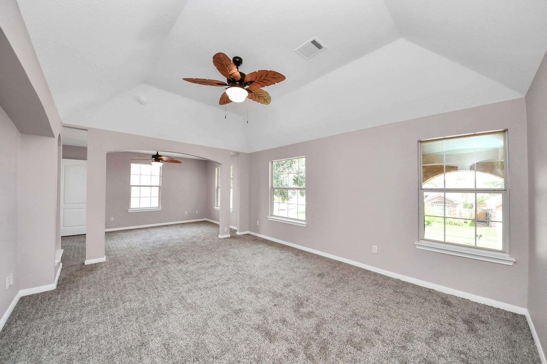 10026 Gil Jr Lane, Houston, TX 77075 Spacious and airy primary living area featuring vaulted ceilings, elegant archways, and abundant natural light, creating a perfect blend of comfort and style.