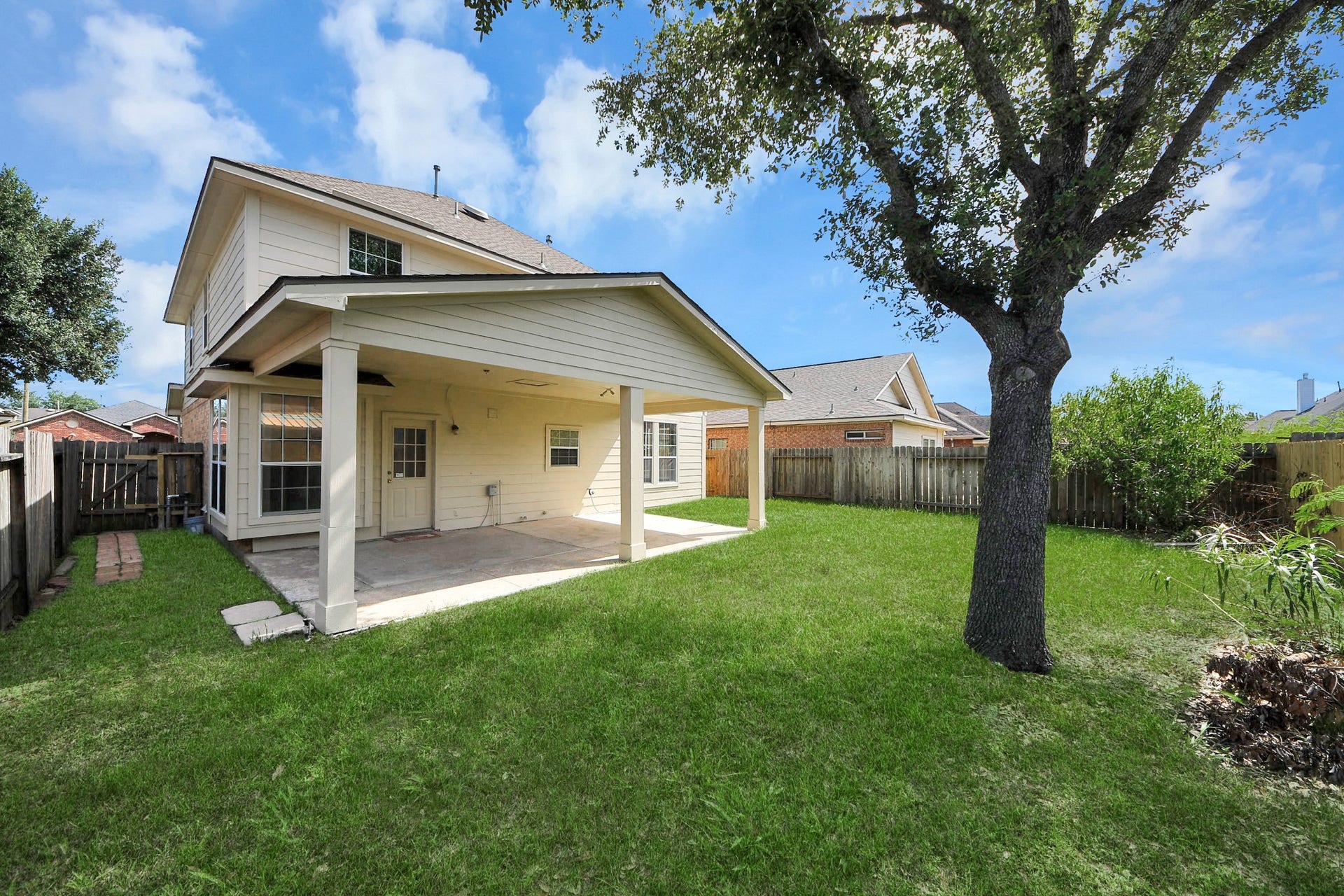 10026 Gil Jr Lane, Houston, TX 77075 Charming two-story home with a spacious covered patio, perfect for outdoor gatherings, set in a lush, fenced backyard shaded by mature trees.