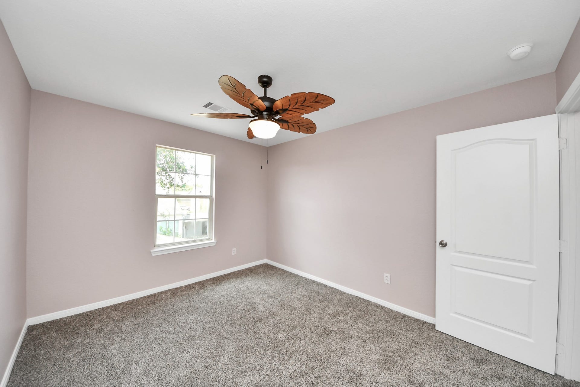 10026 Gil Jr Lane, Houston, TX 77075 Experience comfort and style in this inviting bedroom, featuring plush carpeting, a soothing color palette, and a charming ceiling fan.
