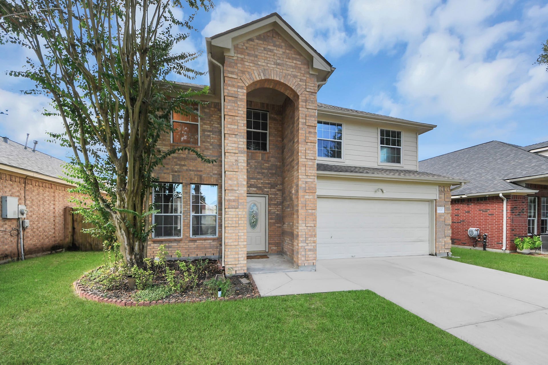 10026 Gil Jr Lane, Houston, TX 77075 Beautiful two-story brick home with a welcoming arched entryway, large windows, and a well-maintained lawn. The attached two-car garage offers convenience and ample parking.