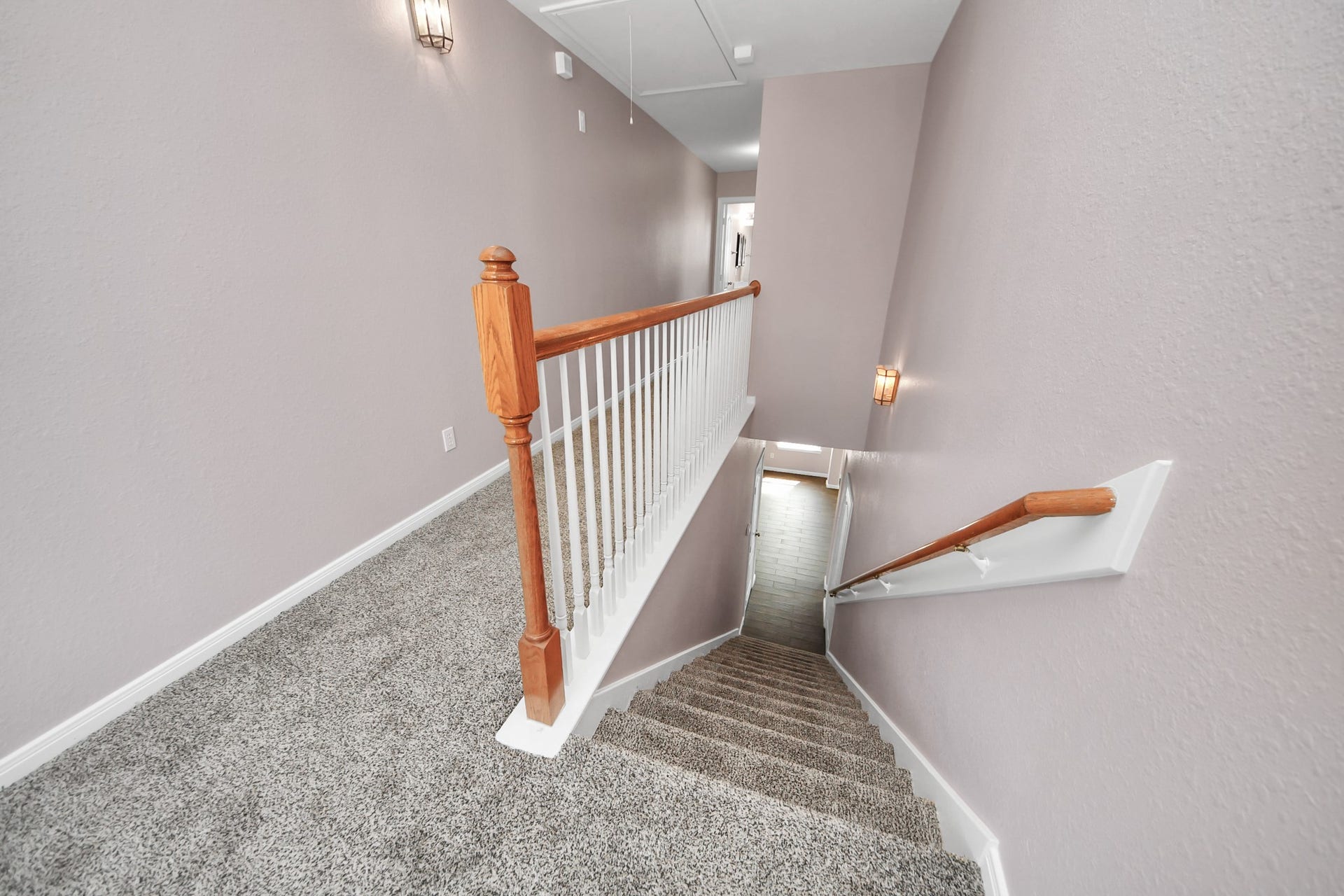 10026 Gil Jr Lane, Houston, TX 77075 Carpeted stairs with a wooden handrail lead to a bright landing, accented by soft wall sconces and neutral wall tones.