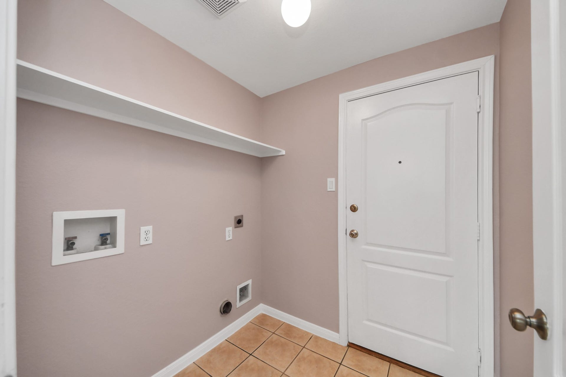 10026 Gil Jr Lane, Houston, TX 77075 Spacious laundry room with hookups, tile flooring, and convenient shelving for storage.