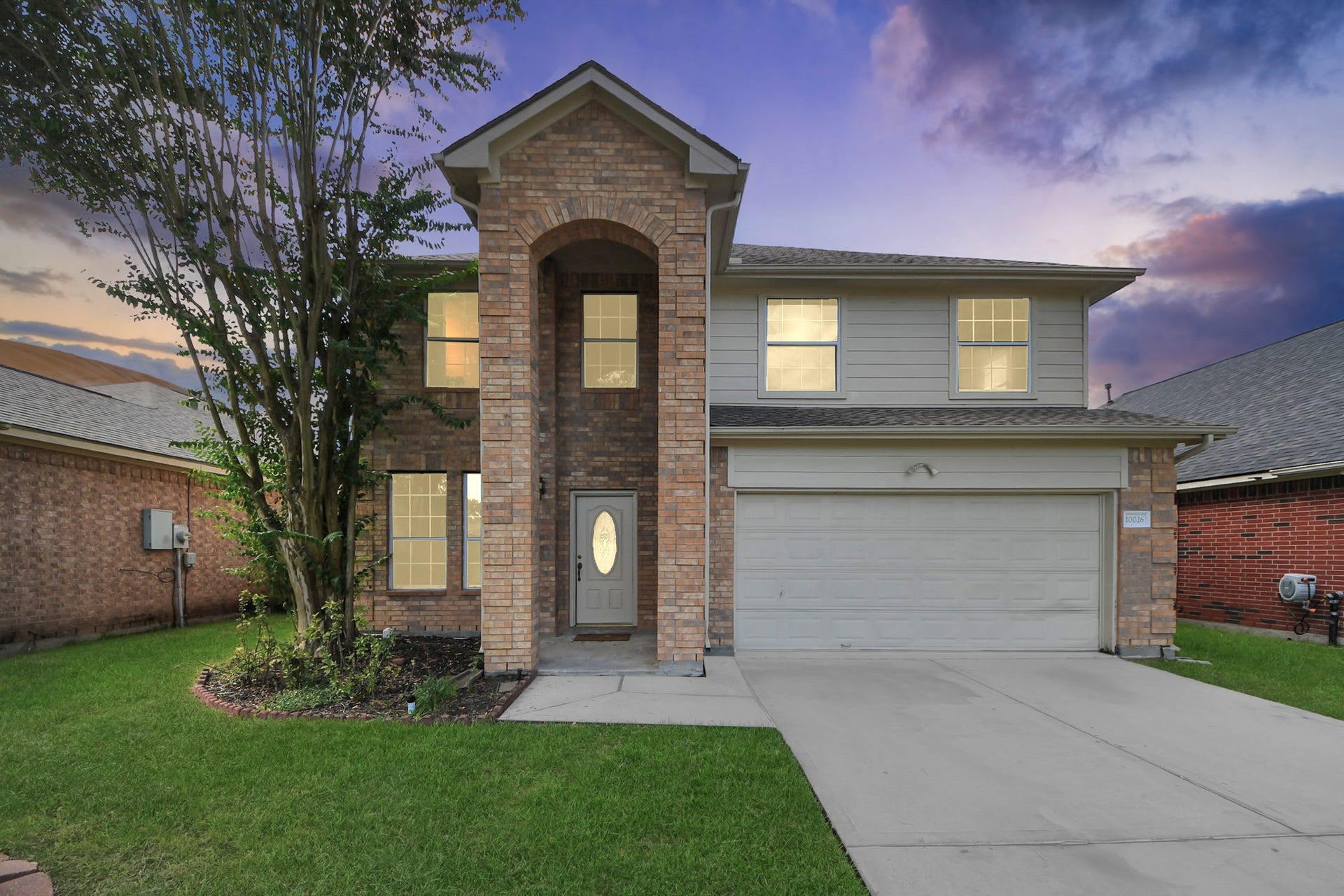 10026 Gil Jr Lane, Houston, TX 77075 Charming two-story brick home with a welcoming archway entrance, nestled in a serene neighborhood with a spacious two-car garage and well-maintained lawn.
