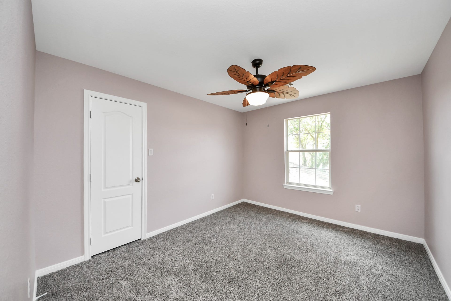 10026 Gil Jr Lane, Houston, TX 77075 Experience comfort in this inviting bedroom featuring plush carpeting, a unique ceiling fan, and abundant natural light through a large window.
