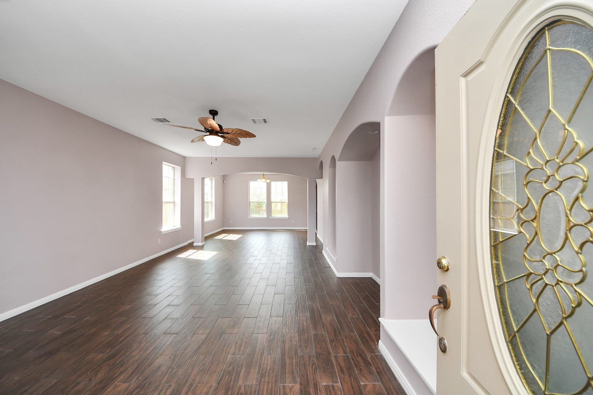 10026 Gil Jr Lane, Houston, TX 77075 Spacious living area with elegant wood tile flooring, abundant natural light, and a decorative ceiling fan, perfect for modern living.