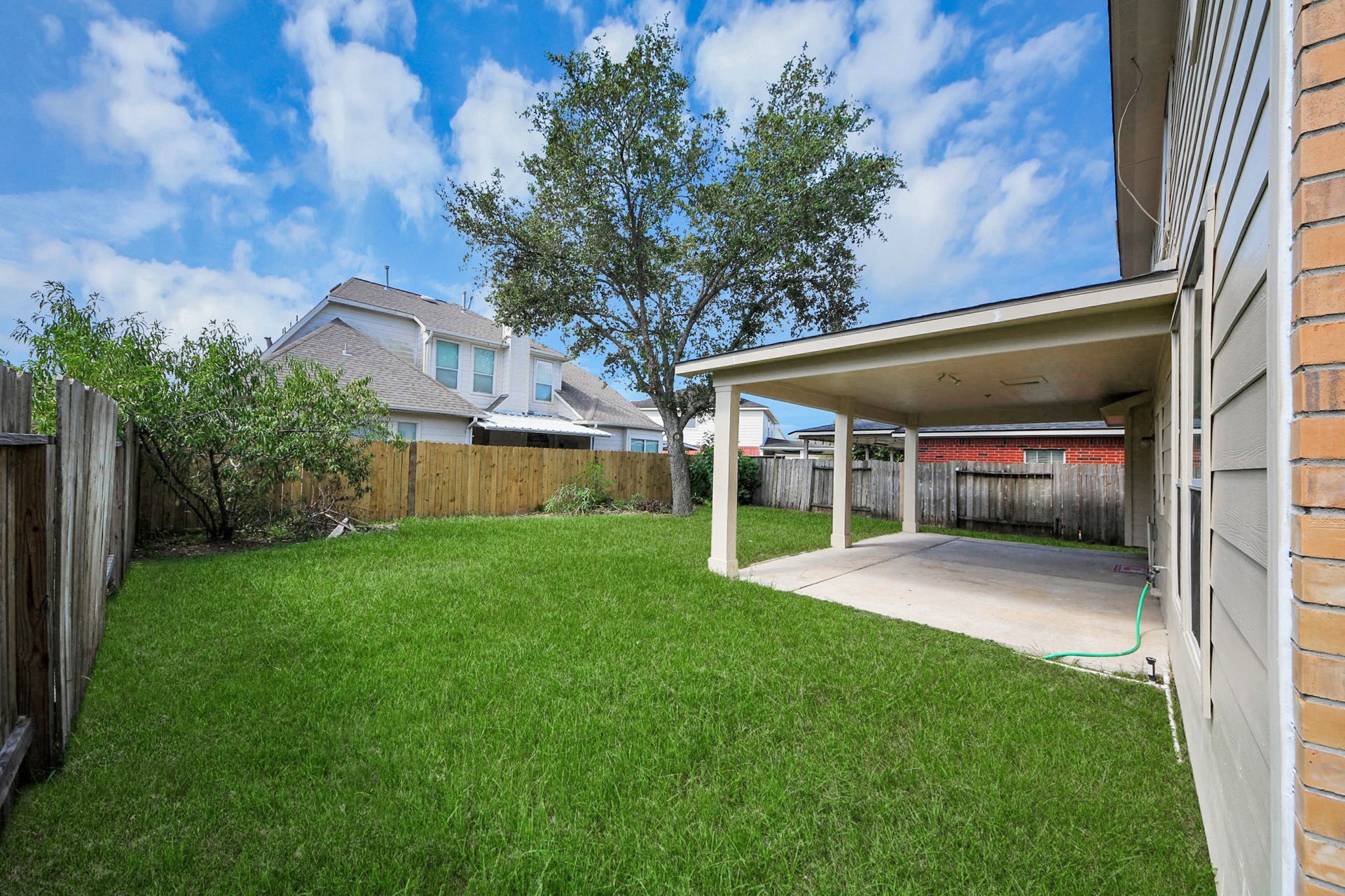10026 Gil Jr Lane, Houston, TX 77075 Spacious backyard with lush green lawn, a covered patio perfect for outdoor gatherings, and privacy fencing for a serene atmosphere.