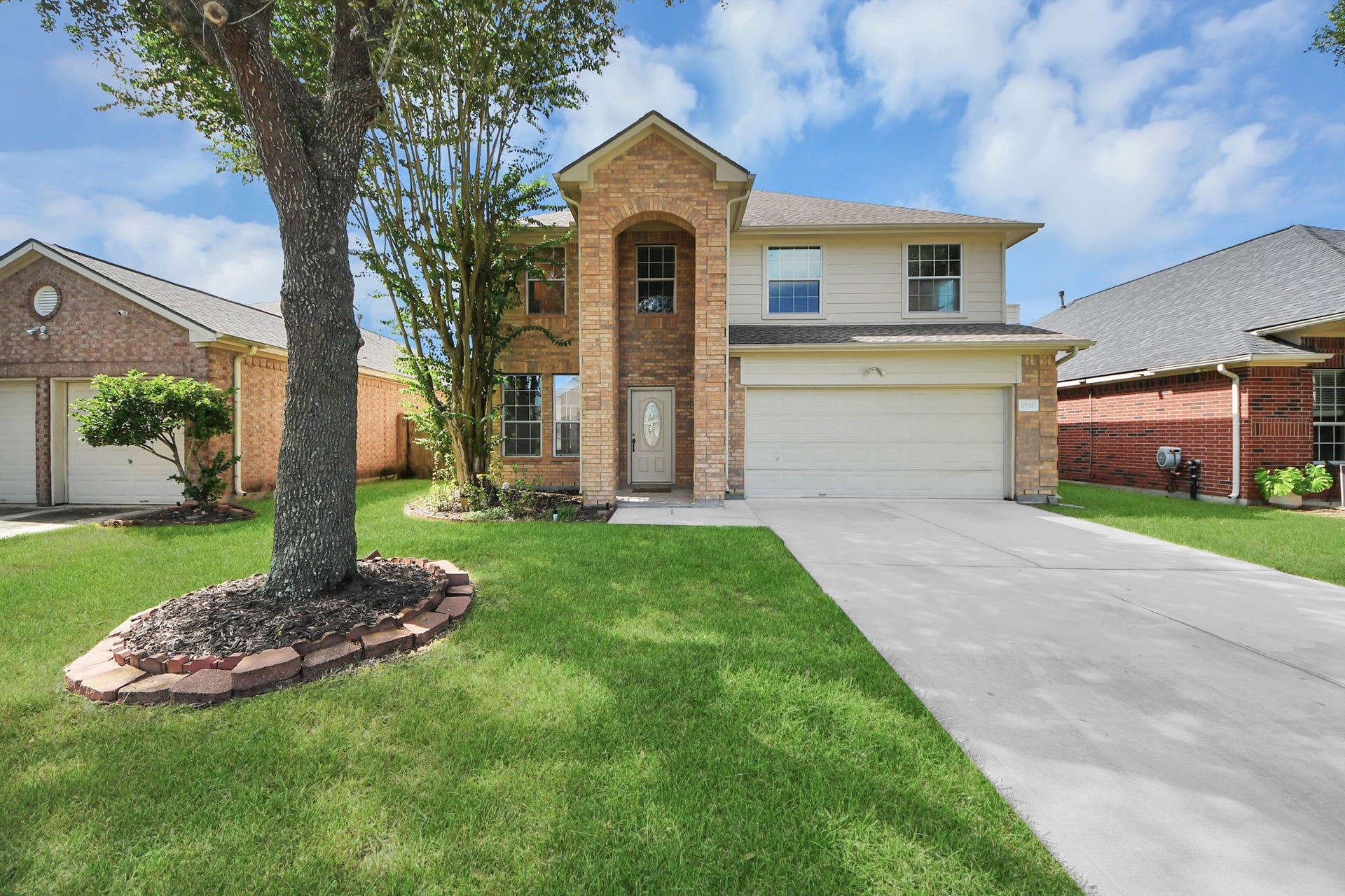 10026 Gil Jr Lane, Houston, TX 77075 Charming two-story brick home with a welcoming arched entry, spacious driveway, and well-maintained front yard accented by mature trees.