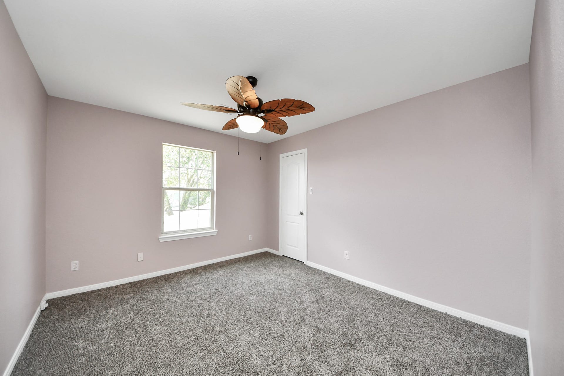 10026 Gil Jr Lane, Houston, TX 77075 Experience the tranquility of Bed 4, featuring soft lavender walls, plush carpeting, and a charming ceiling fan, perfect for restful nights.