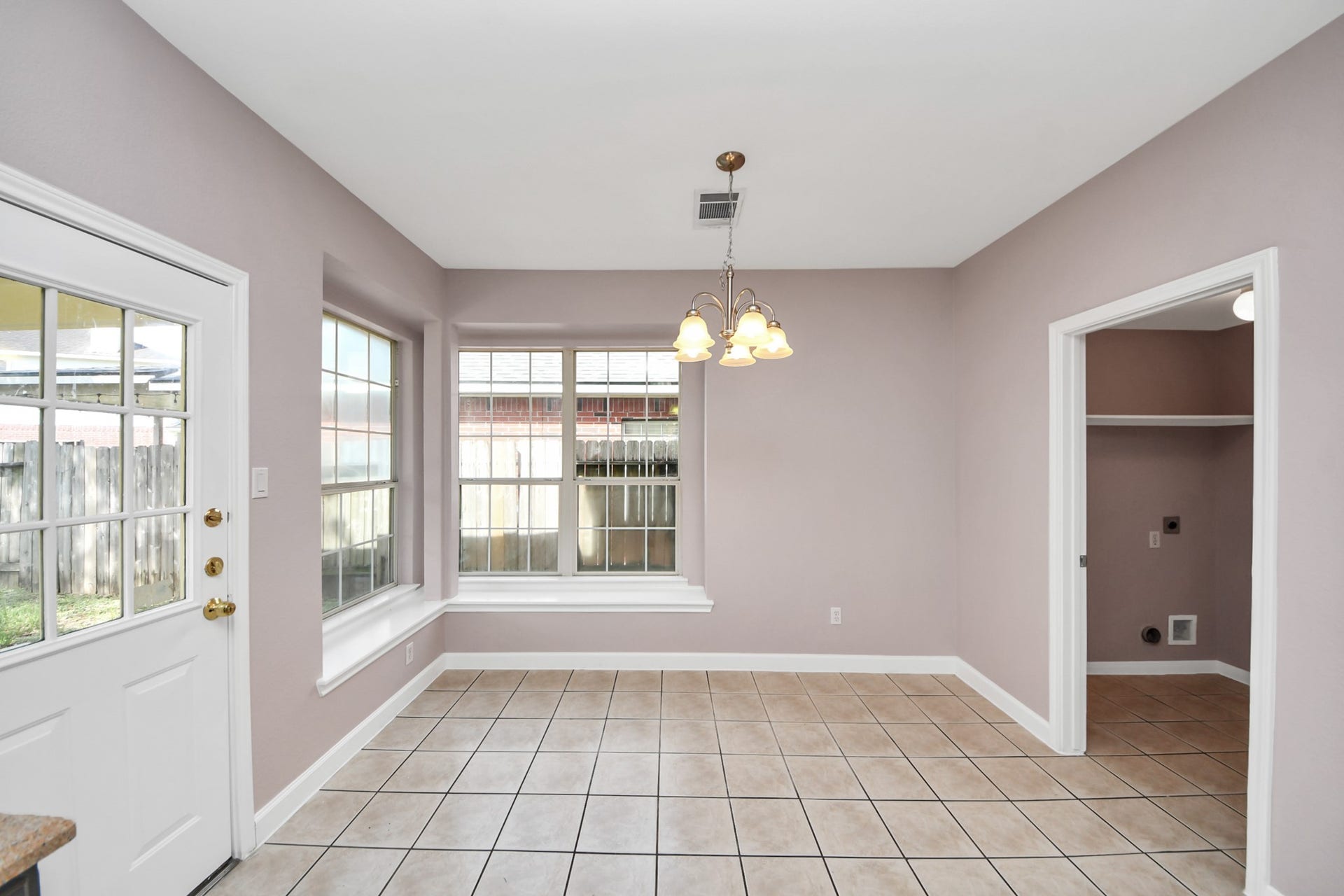 10026 Gil Jr Lane, Houston, TX 77075 Bright and inviting dining area with large windows, tile flooring, and a stylish light fixture, offering easy access to the backyard through a side door.