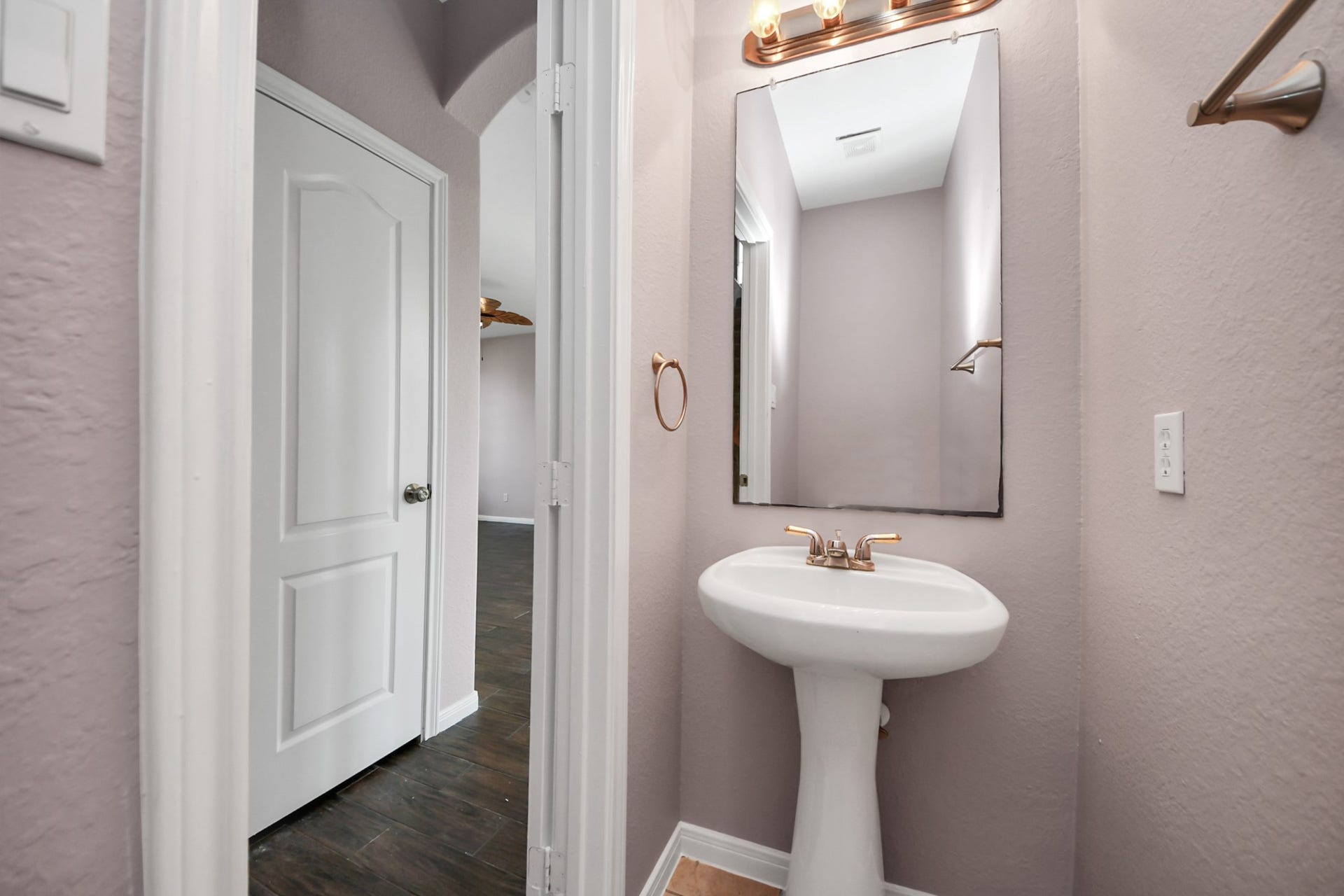 10026 Gil Jr Lane, Houston, TX 77075 Charming half-bathroom features a pedestal sink, elegant mirror, and warm lighting, complemented by soft, neutral walls.