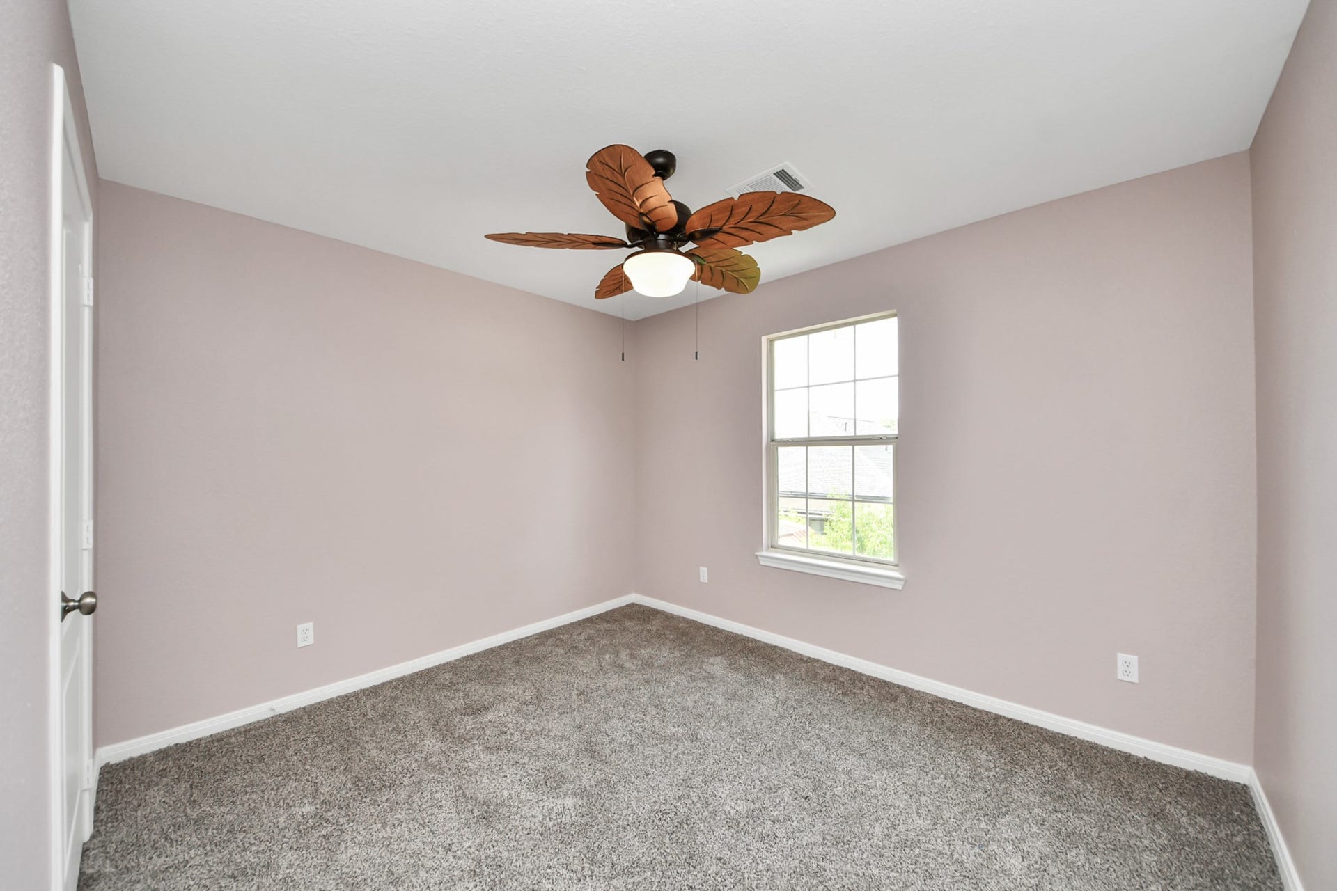 10026 Gil Jr Lane, Houston, TX 77075 Bright and inviting, this spacious bedroom features plush carpeting, soft pastel walls, and a unique ceiling fan, offering a cozy retreat with ample natural light.