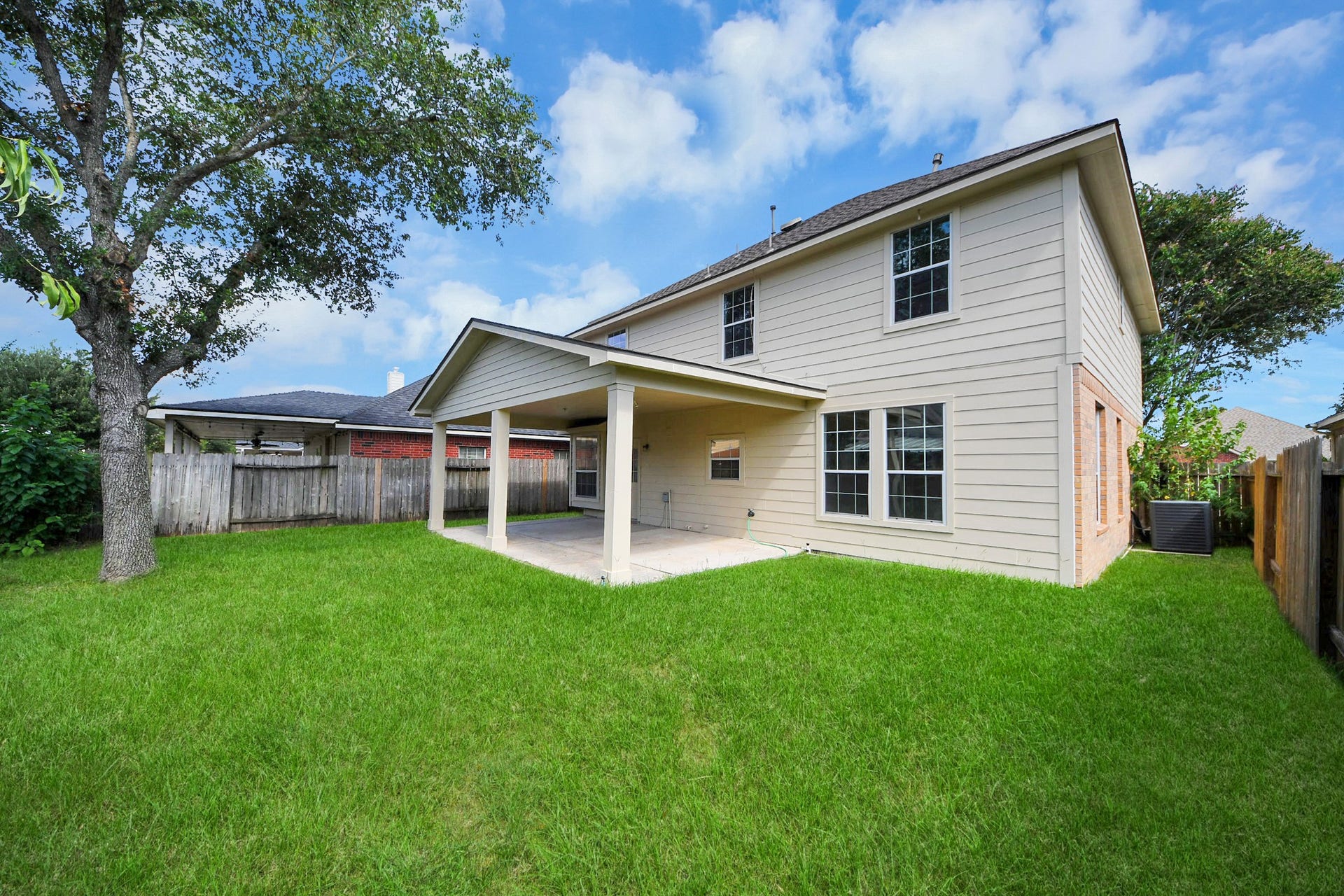 10026 Gil Jr Lane, Houston, TX 77075 Spacious backyard with a covered patio, perfect for outdoor gatherings, complemented by a well-maintained lawn and privacy fencing.