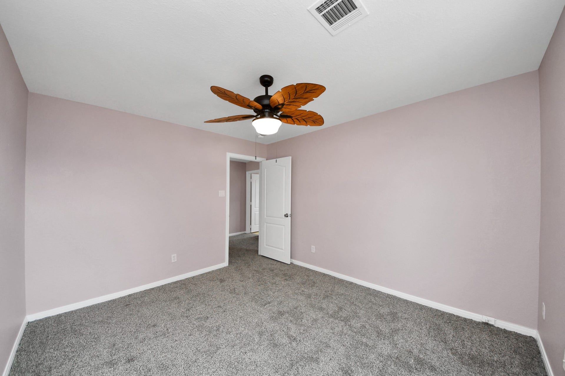 10026 Gil Jr Lane, Houston, TX 77075 Experience tranquility in this spacious bedroom featuring soft lavender walls, plush carpet, and a stylish leaf-inspired ceiling fan.