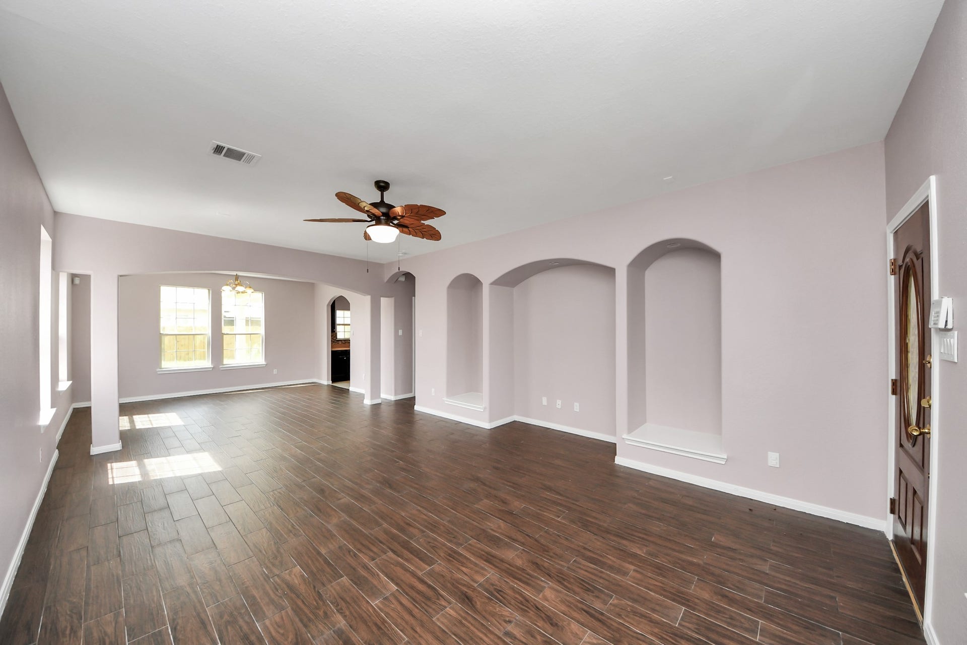 10026 Gil Jr Lane, Houston, TX 77075 Spacious living area with rich wood-look flooring, built-in alcoves, and abundant natural light from large windows.