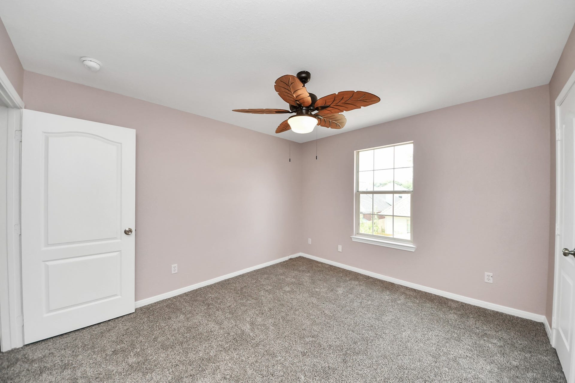 10026 Gil Jr Lane, Houston, TX 77075 Discover the charm of this cozy bedroom featuring plush carpeting, a tropical ceiling fan, and abundant natural light.