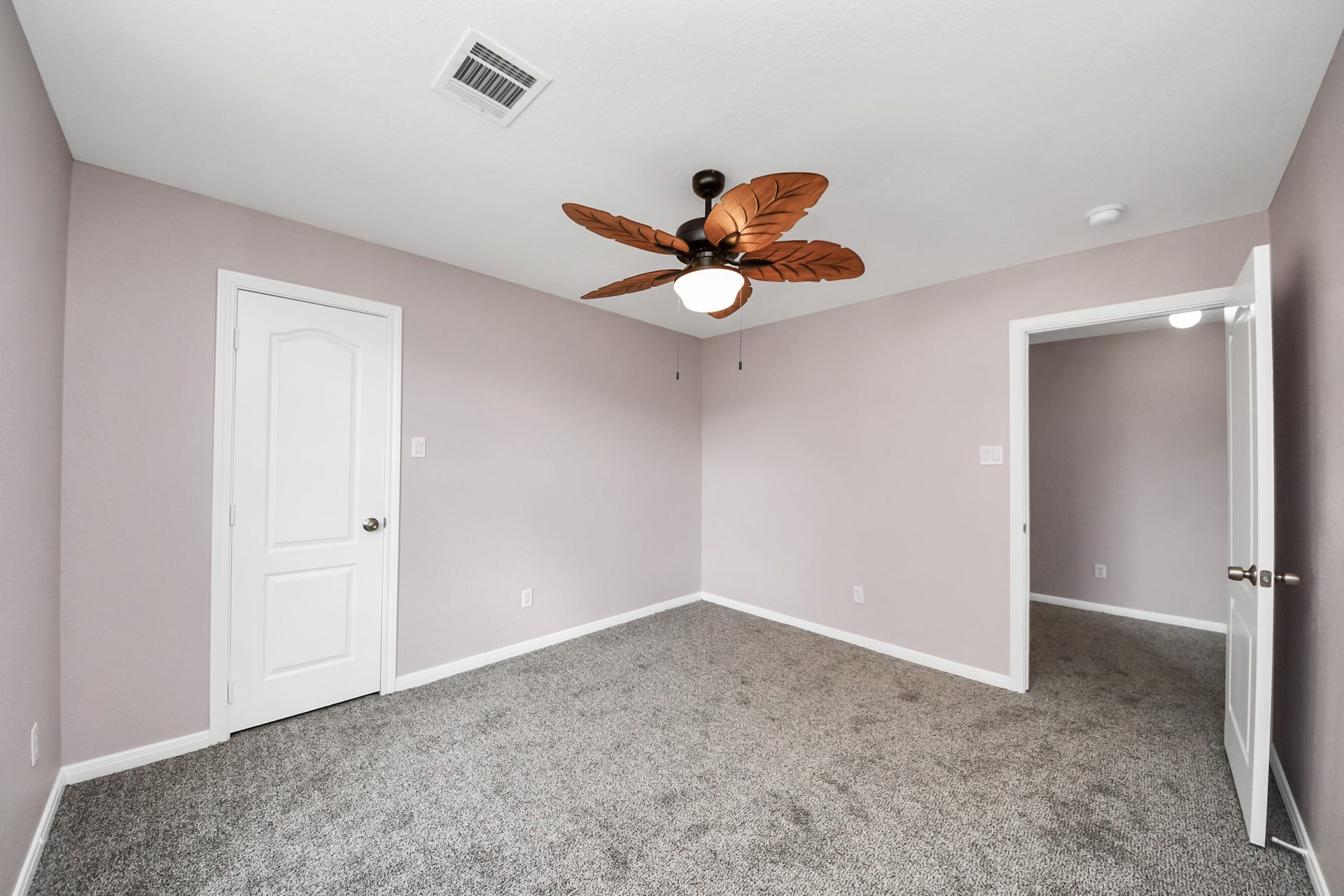 10026 Gil Jr Lane, Houston, TX 77075 Discover tranquility in this cozy bedroom featuring soft lavender walls, plush carpeting, and a stylish ceiling fan for the perfect retreat.
