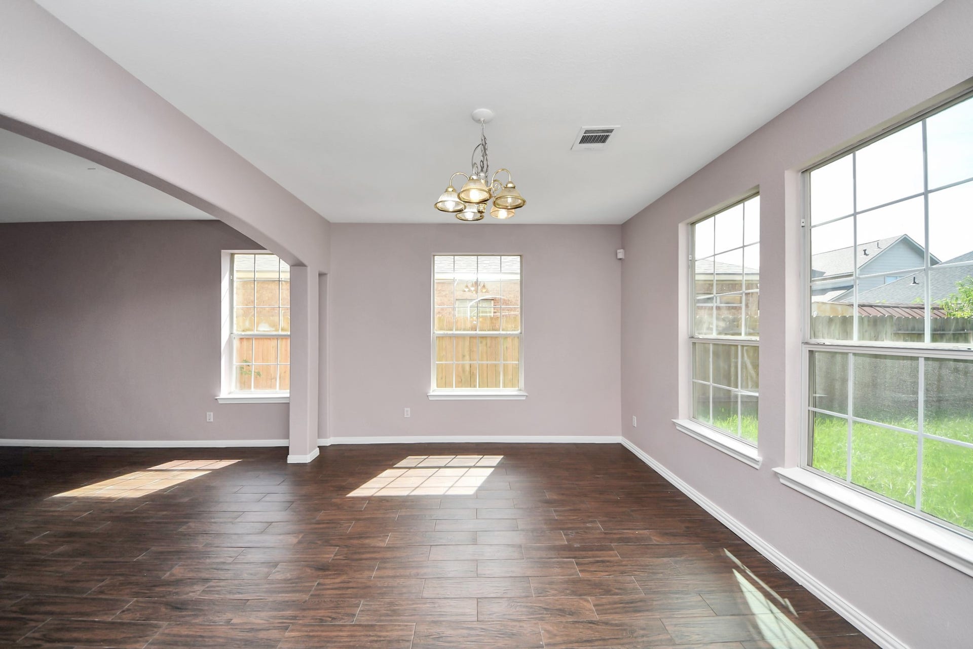 10026 Gil Jr Lane, Houston, TX 77075 Bright and spacious living area with large windows, elegant wood-look flooring, and a stylish chandelier, perfect for entertaining and relaxation.